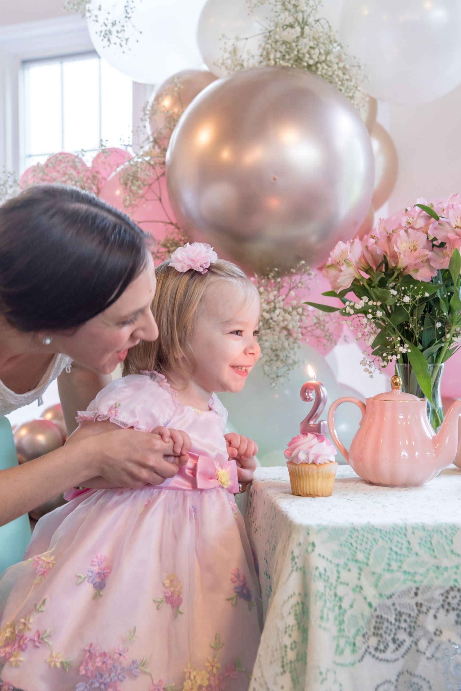 A pink and gold balloon decorated tea party setting with floral arrangements and delicate details.