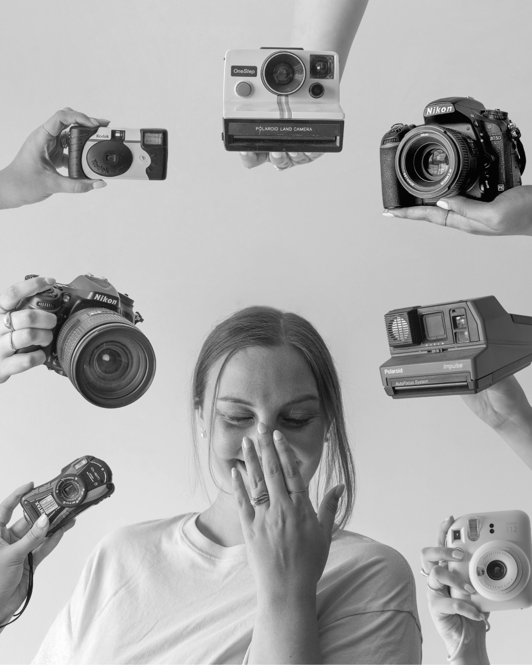 Woman covering face surrounded by multiple cameras in black and white photography studio setting.