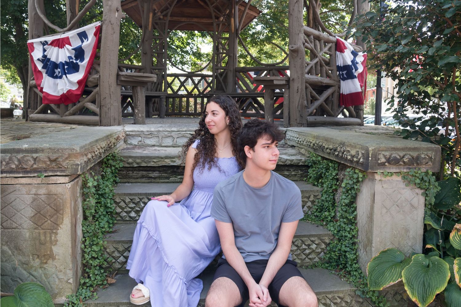 Two people sit together on outdoor steps decorated with patriotic bunting.