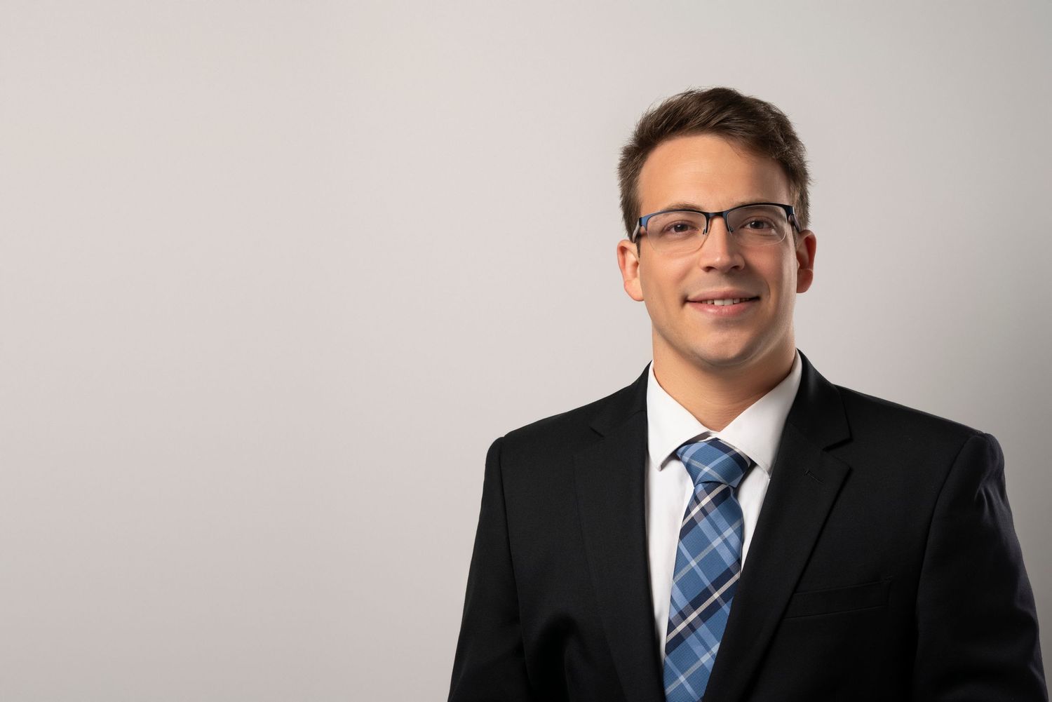 Professional business portraits showing suited figures with matching blue plaid ties against a light gray background.