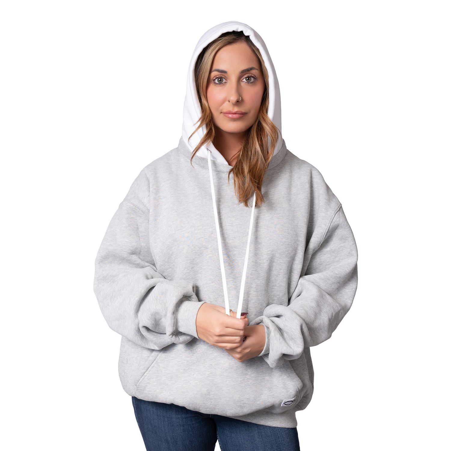 Person wearing an oversized light gray hoodie sweatshirt with drawstrings and blue jeans in a casual pose.