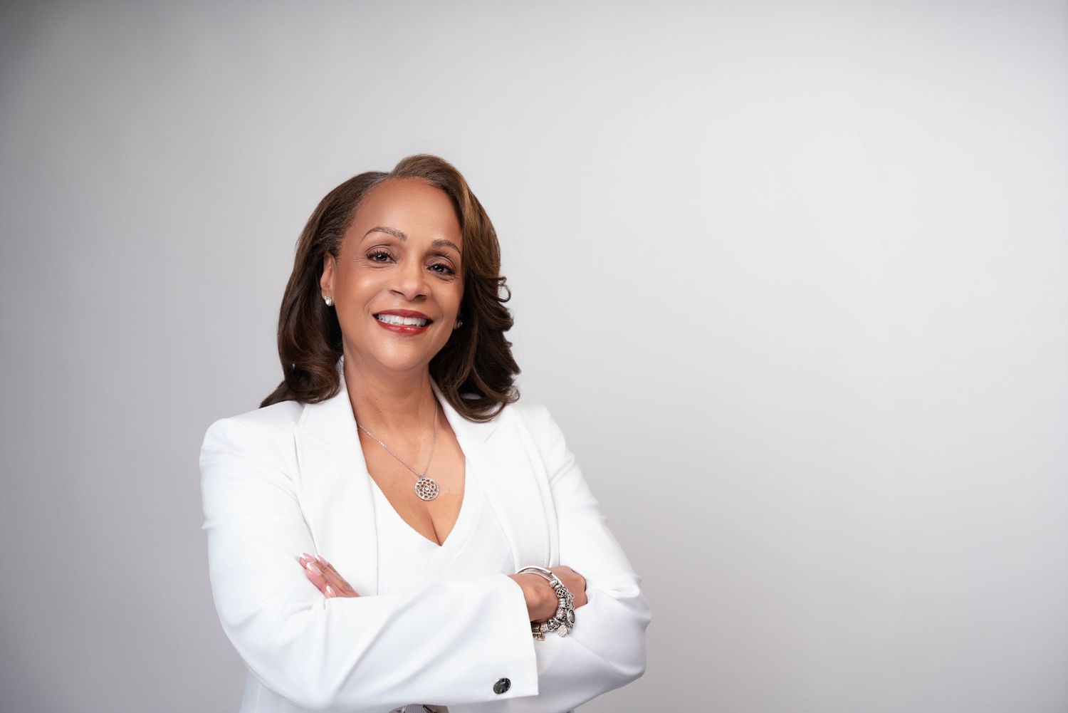 Professional studio portraits with a person in a white business outfit shown from different angles against a gray background.