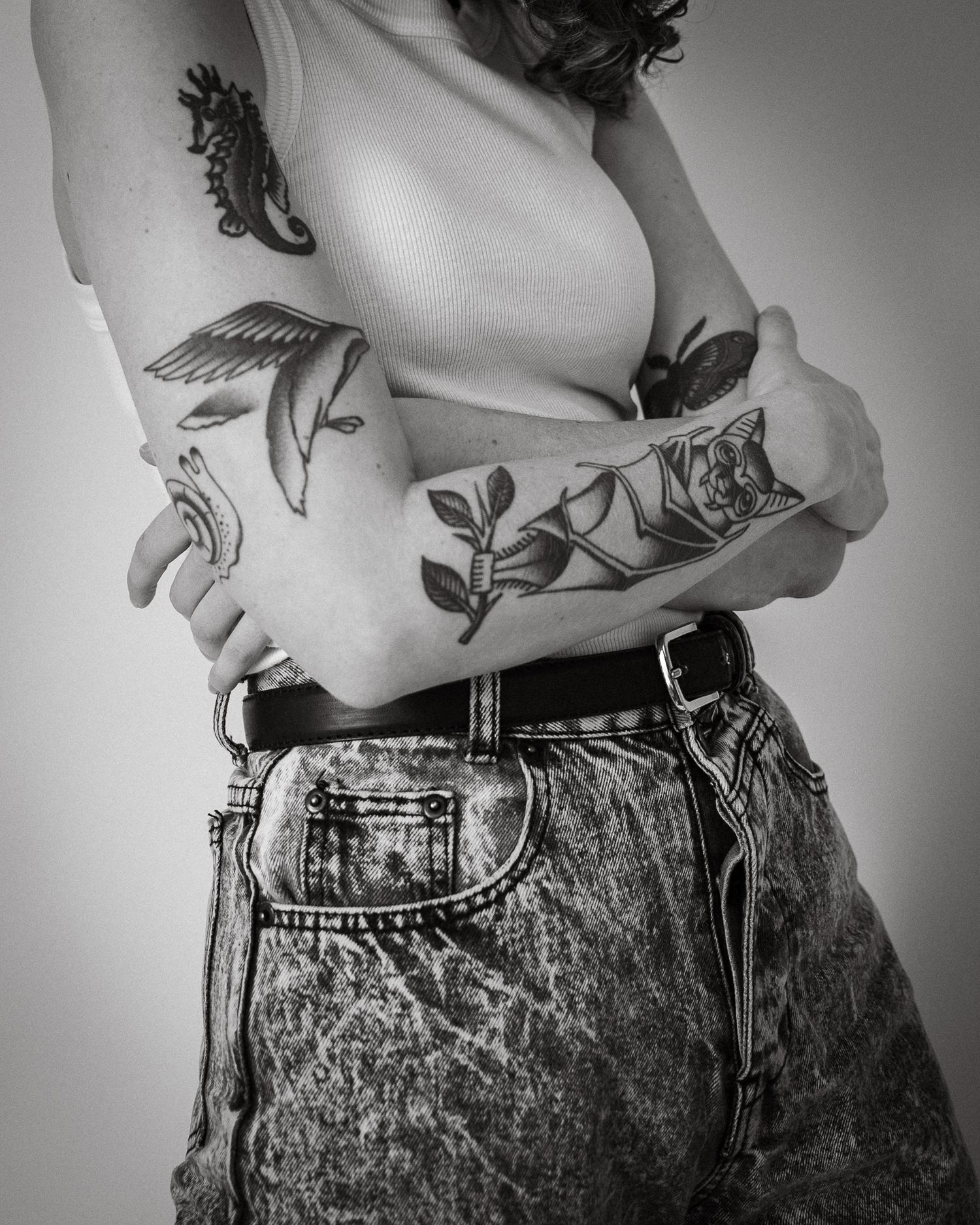 A black and white photo of the midsection of a human with tattoos.