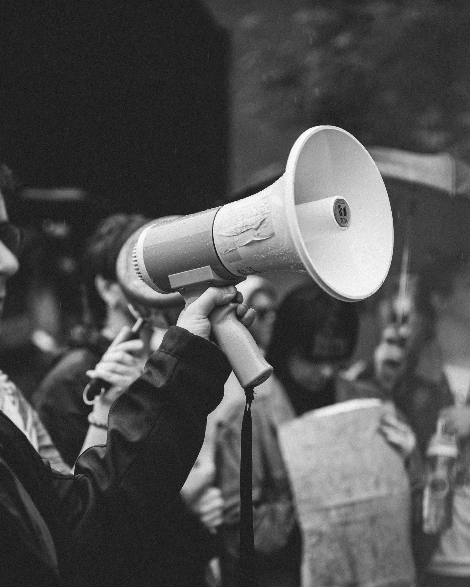 A black and white photo of a megaphone held up in a crowd.