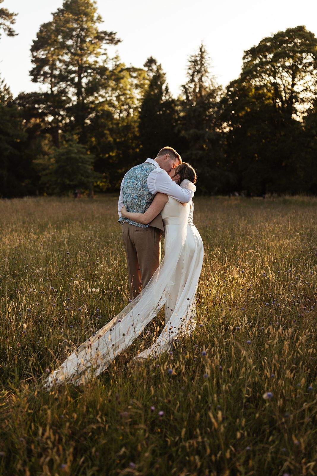 Couple kiss in field at Plas Dinam Country House in Wales. Authentic wedding portraits.