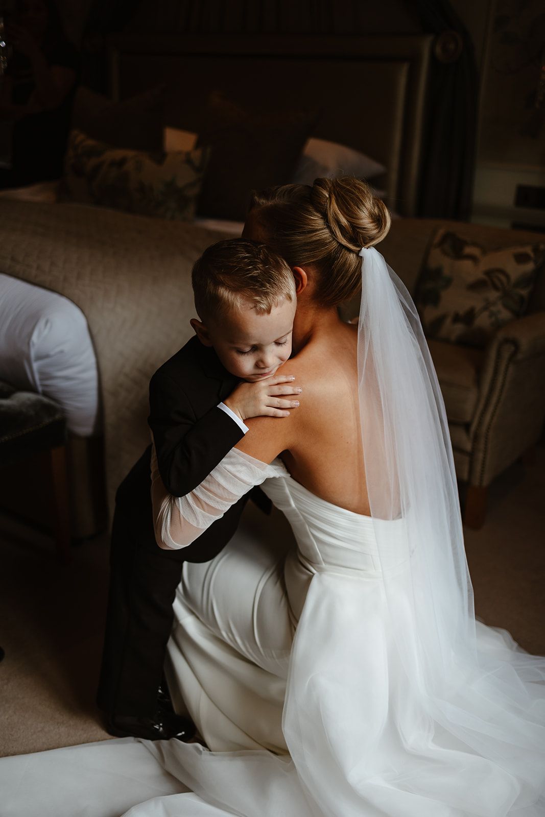 Bride hugs son on wedding morning. Bride wears beautiful veil.