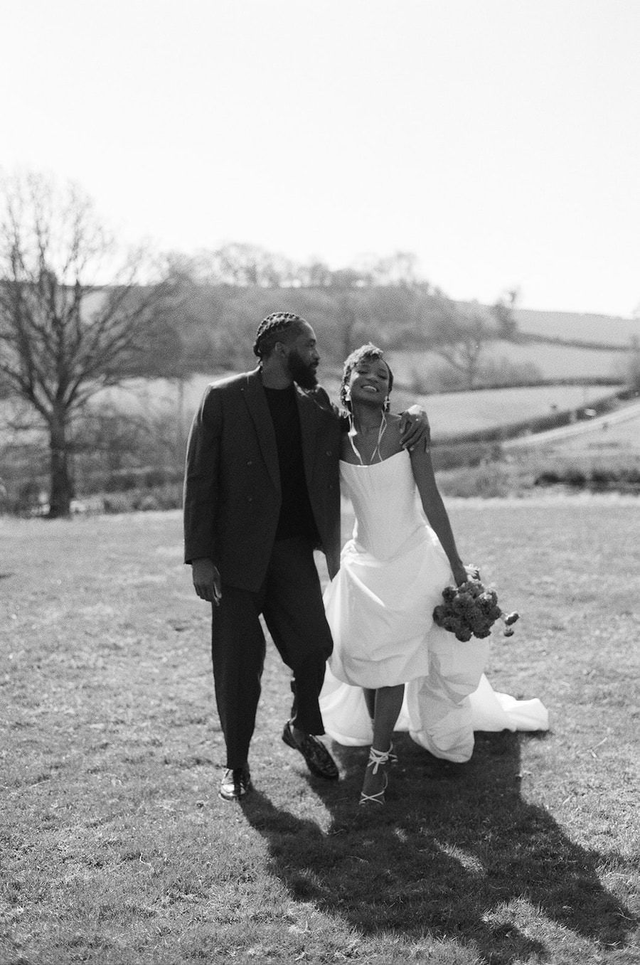 35mm Film of couple walking through a field at wedding.
