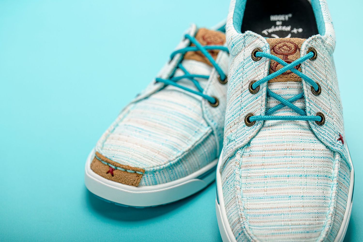 Stylish baby boat shoes in white and aqua blue stripes with brown leather accents and teal laces.