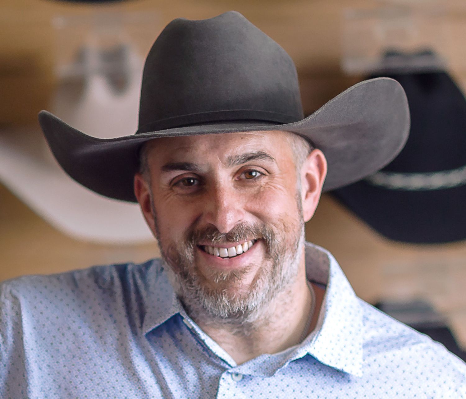 Professional headshot series of person in cowboy hat showing different expressions.