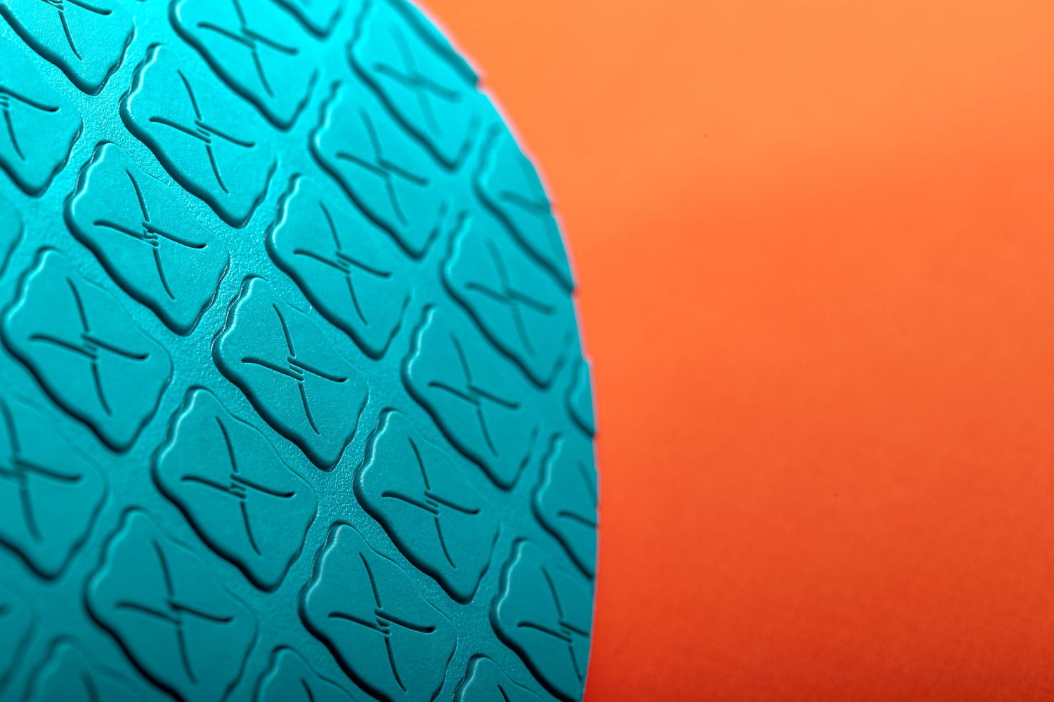 Abstract teal boomerang shapes against vibrant orange background create dynamic geometric pattern.