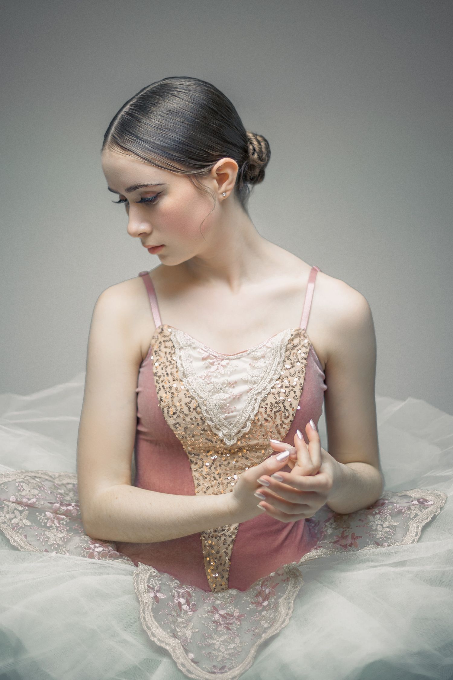 Elegant ballet dancer in pink and gold tulle costume against grey backdrop. Editorial Portrait Photography