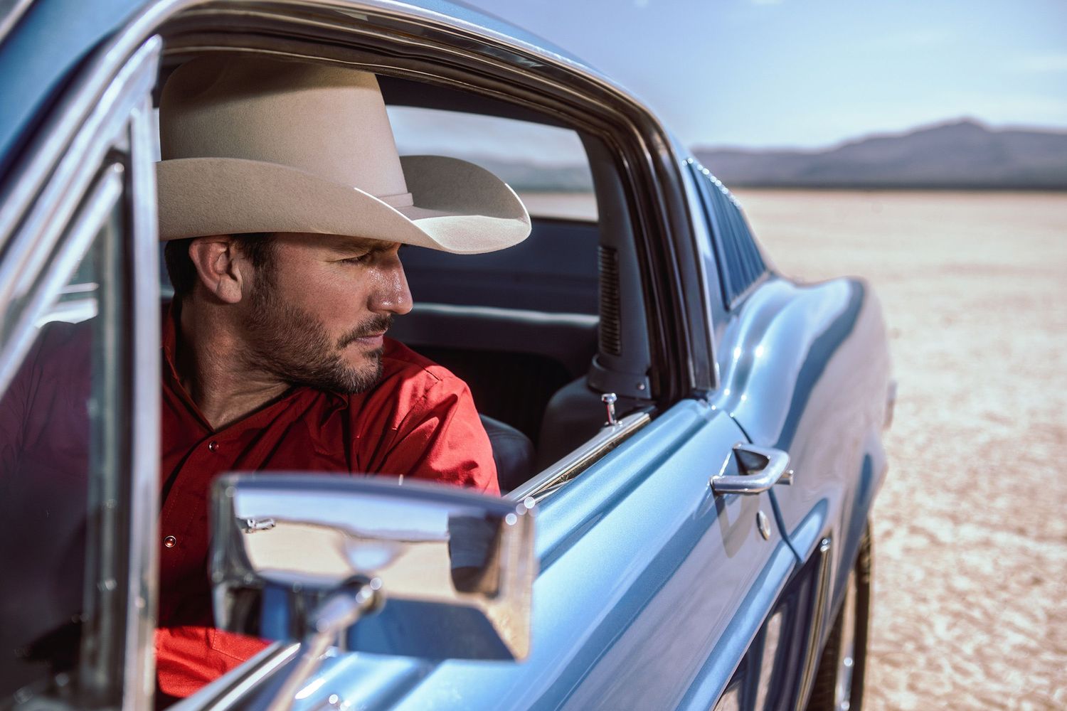 Master Hatters of Texas 1968 Hat Campaign image of a cowboy in a 1968 Ford Mustang Fastback car on a dry lakebed. Product Lifestyle