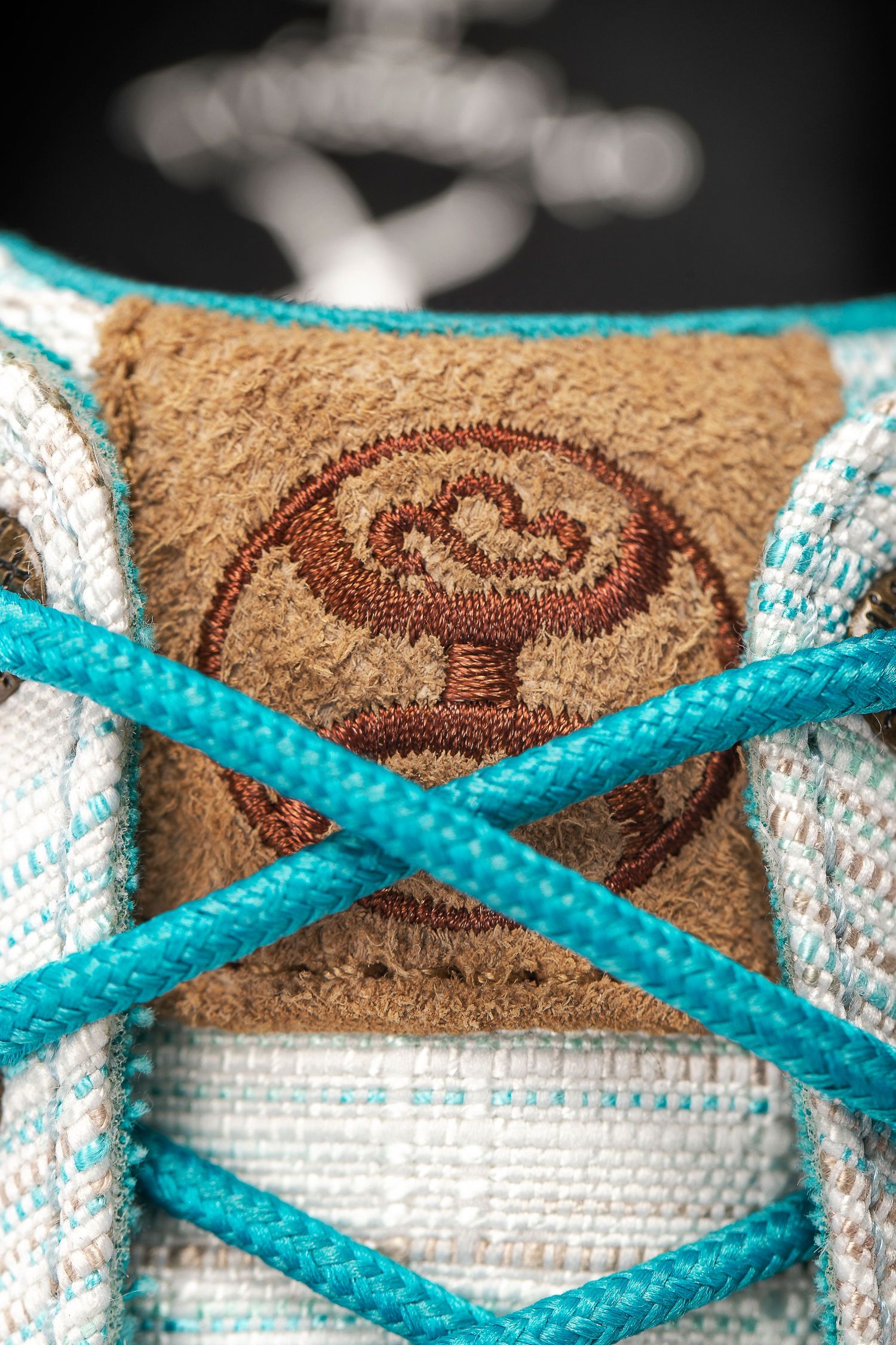 A white and turquoise sneaker with detailed brown leather showing decorative pattern closeup macro shots.