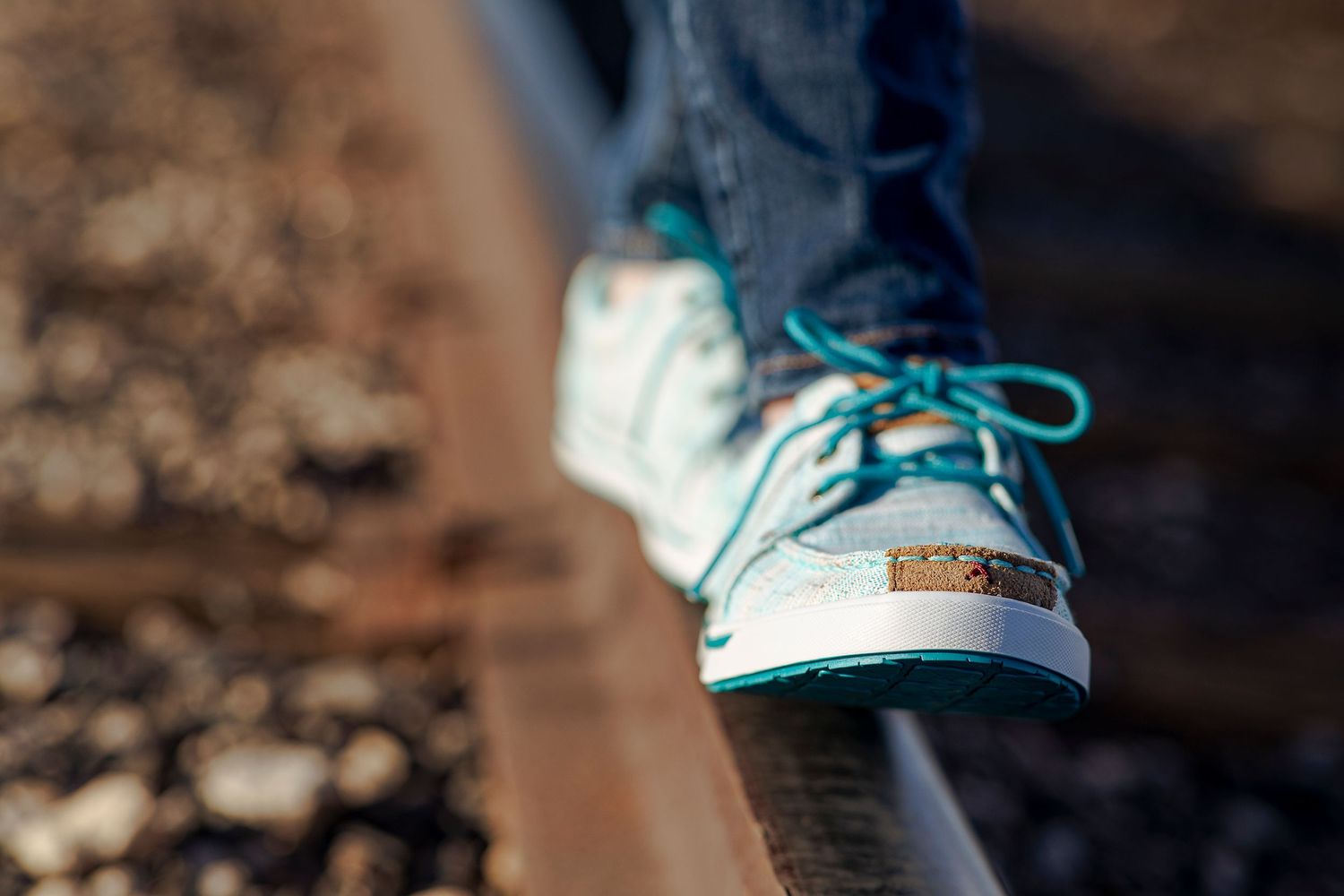 A close-up view of light blue sneakers with matching laces against a blurred background.