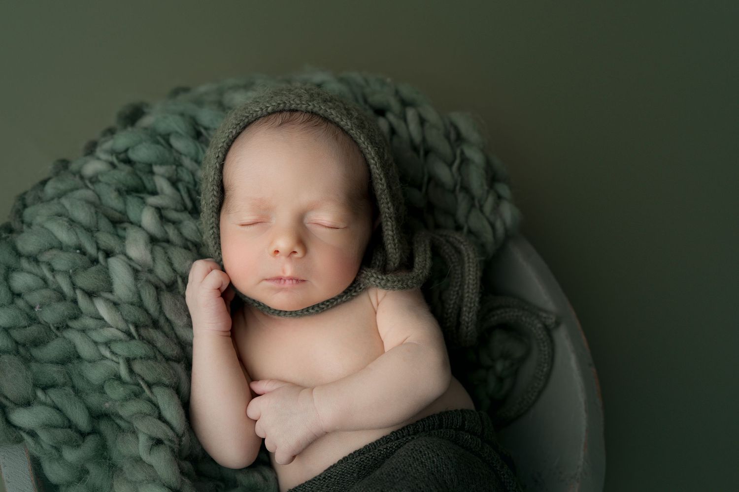 Newborn snuggled in green bowl. Hatched newborn photography. Wisconsin's premiere newborn and maternity photography.
