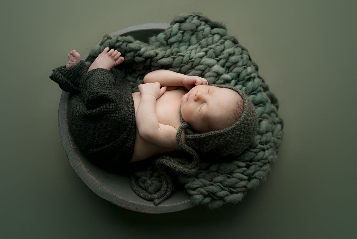 Newborn snuggled in green bowl. Hatched newborn photography. Wisconsin's premiere newborn and maternity photography.