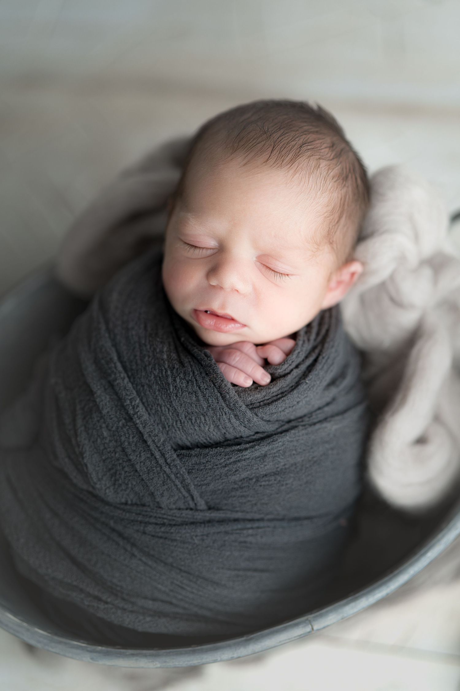 Baby snuggled in a grey knit wrap sleeping soundly. Newborn photo. Hatched Newborns. Madison, Mount Horeb, Verona, Middleton, Wisconsin.