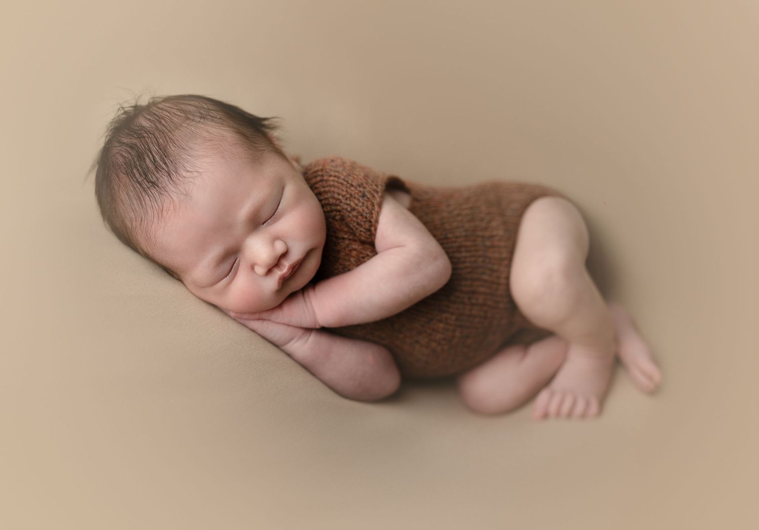 Baby asleep on a brown backdrop. Snuggled in a romper. Baby on green backdrop. Hatched Newborn and Family Photography. Madison, Wi