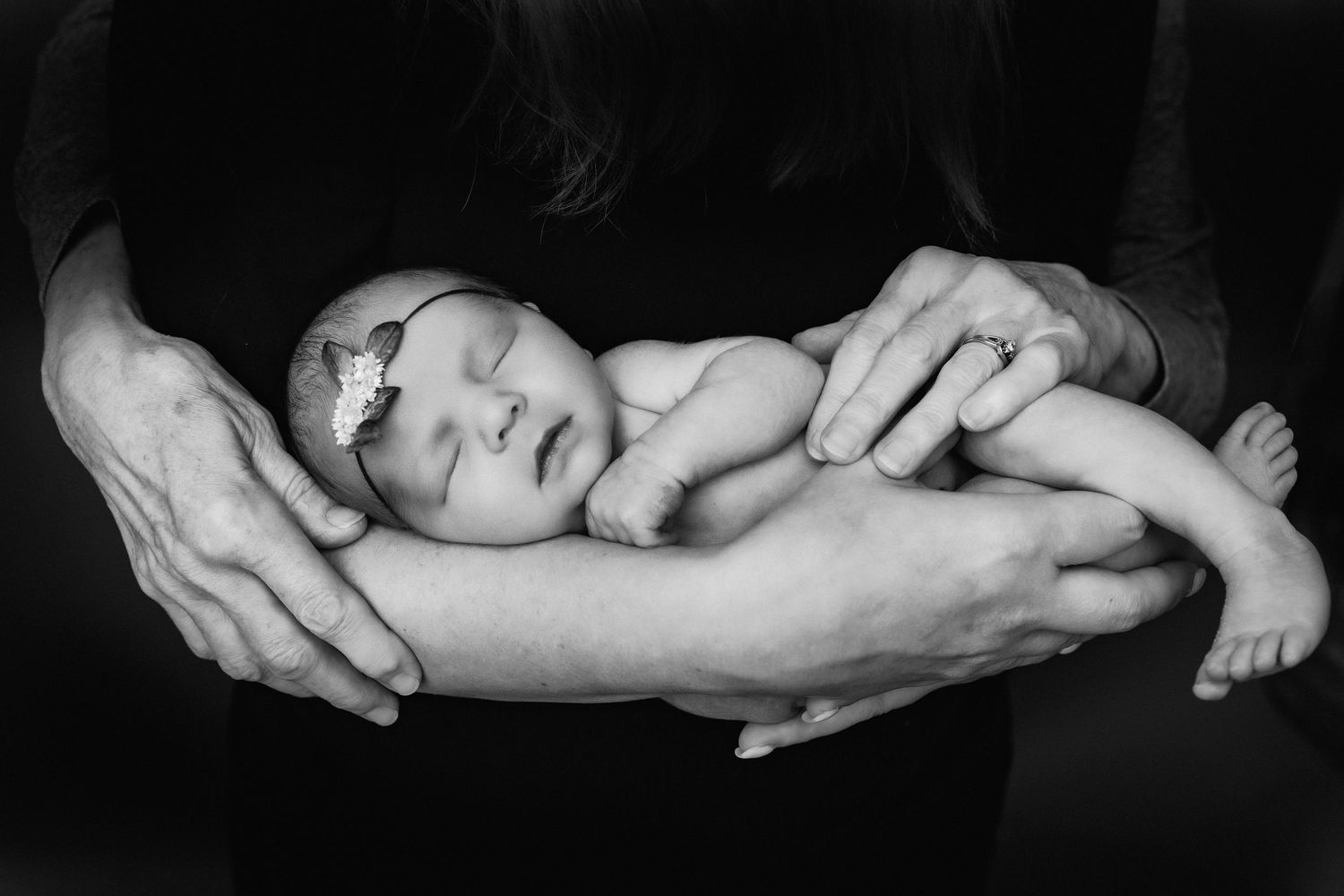 dramatic black and white photo of baby and parent's hands