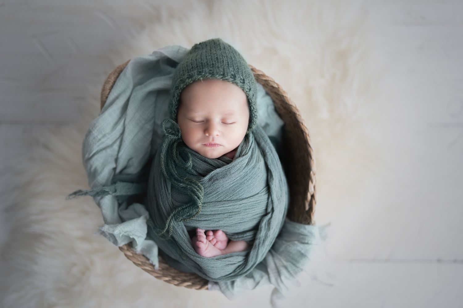 Baby in teal, snuggled in a basket. Hatched Newborn Photography