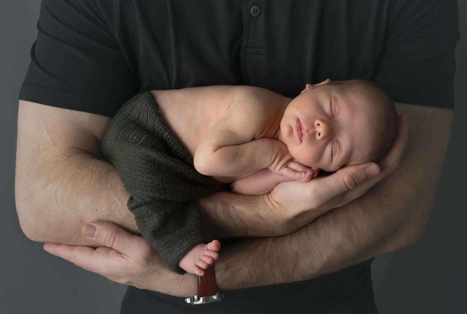 newborn snuggled in father's arms. Family newborn photos. Hatched newborn photography. Wisconsin's premiere newborn photography.