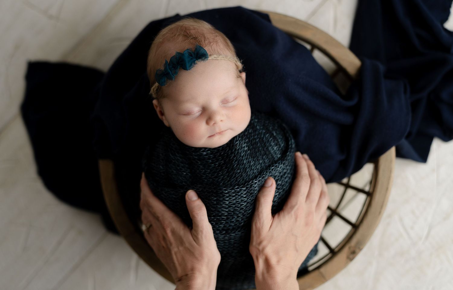 Gorgeous baby in navy blue with mother's hands.