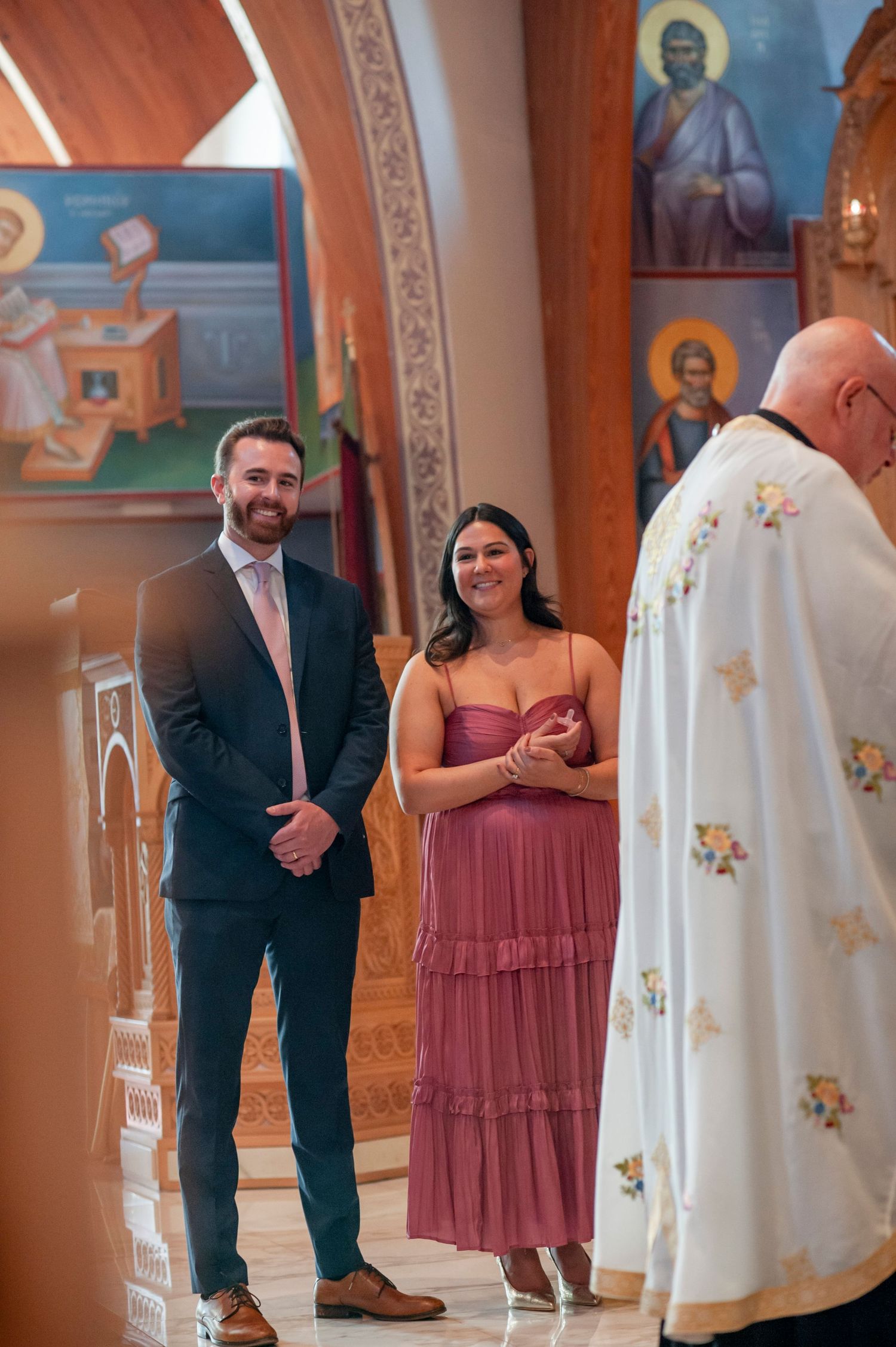 People gather in an ornate church interior with religious icons and decorative elements visible on the walls.