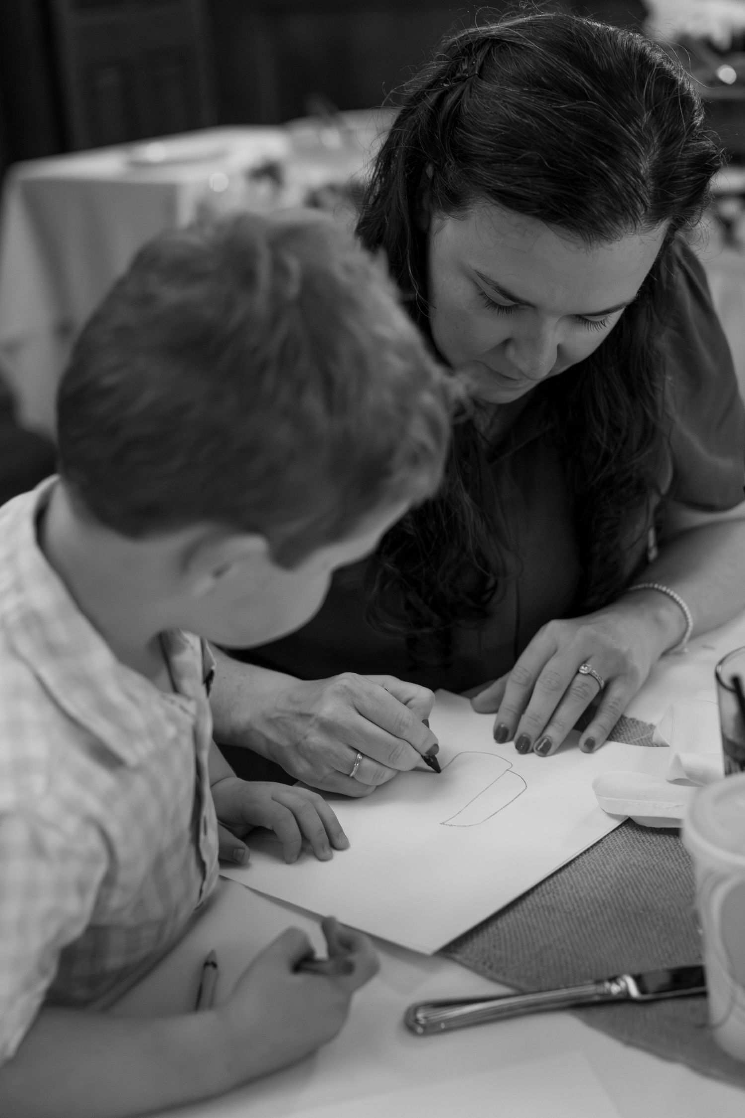 Black and white series of people writing or drawing together at a table.