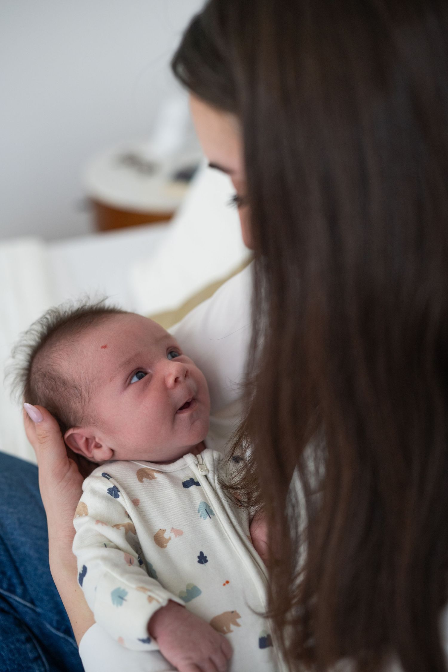 Close-up shots of a newborn baby in patterned onesie being held.