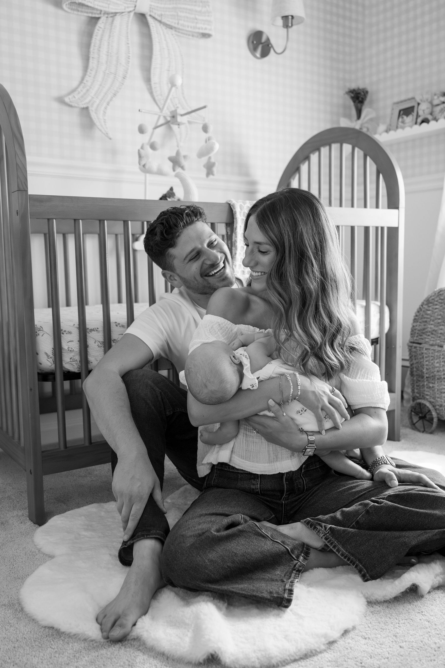 Candid black and white photo series showing intimate family moments on a plush carpet in a nursery.