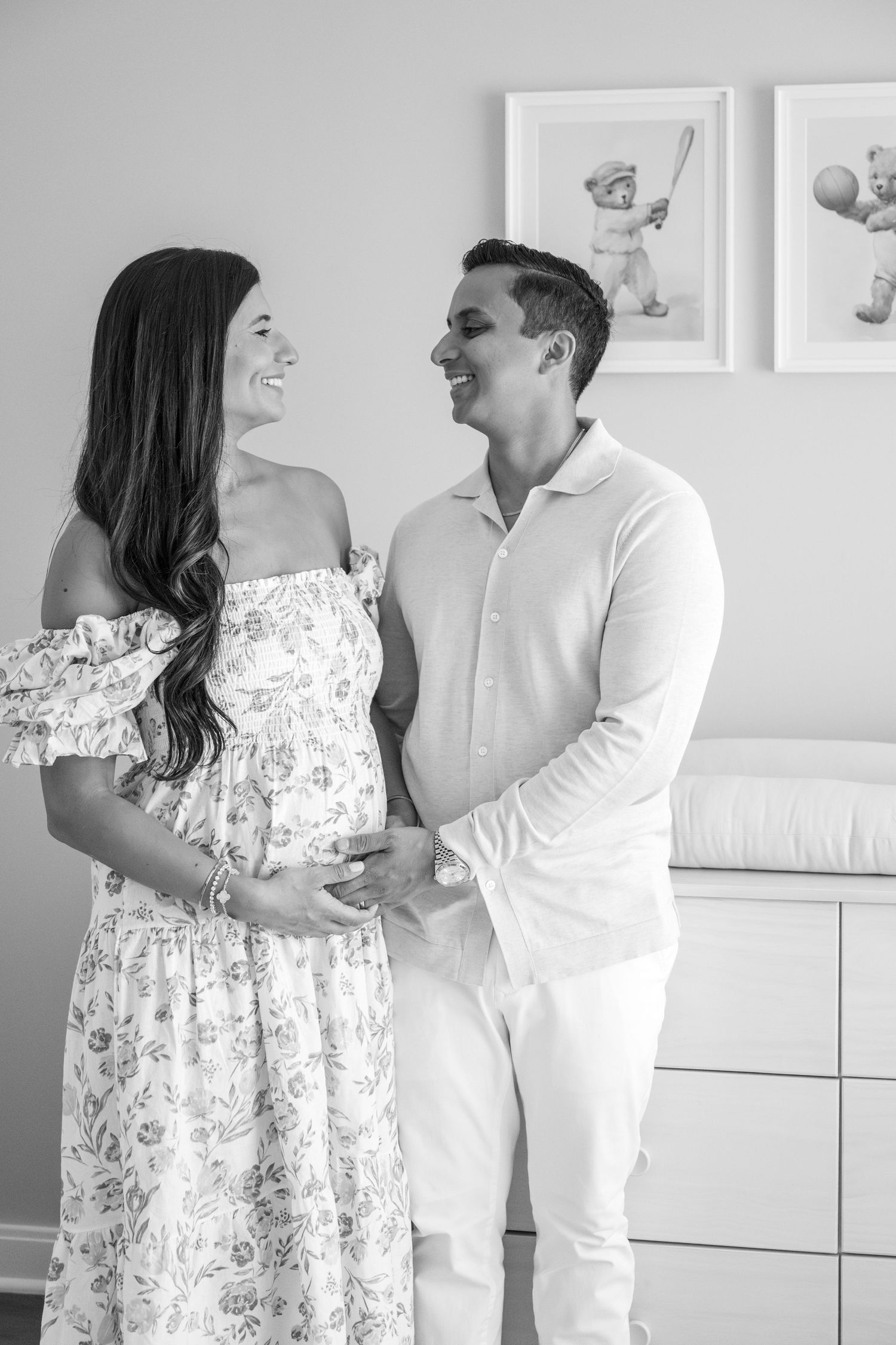 Candid shots of couple laughing together in modern nursery with baby artwork.