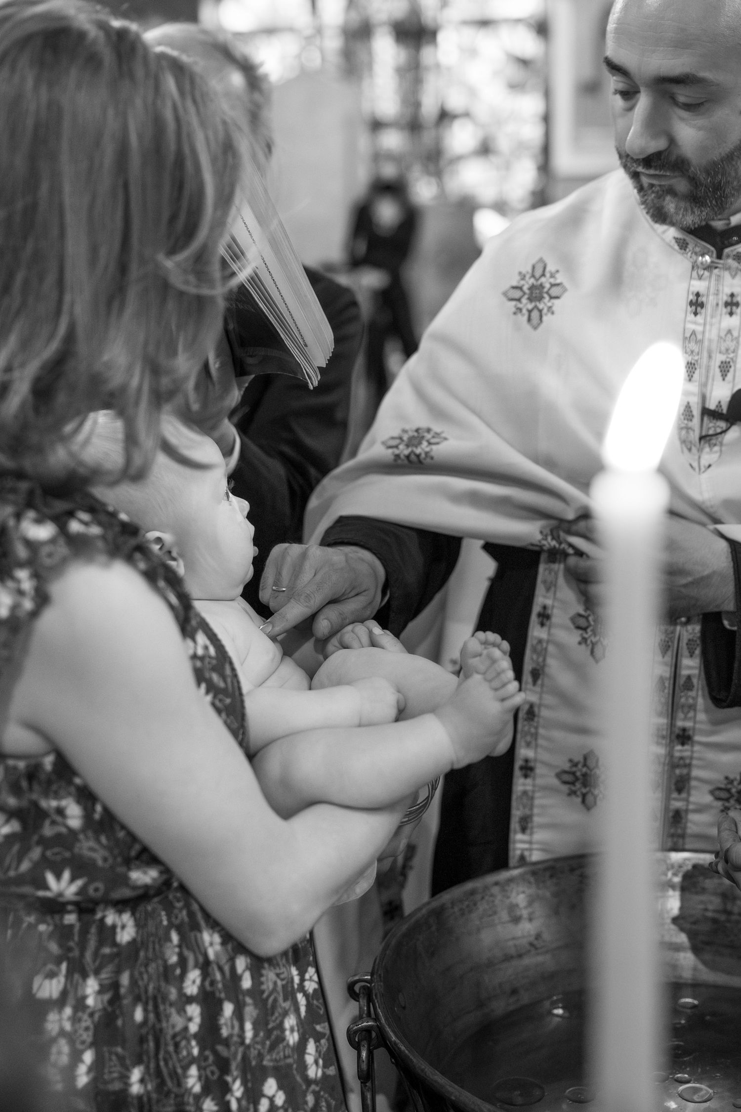 Close-up details of a baptismal ceremony showing hands and traditional religious garments.