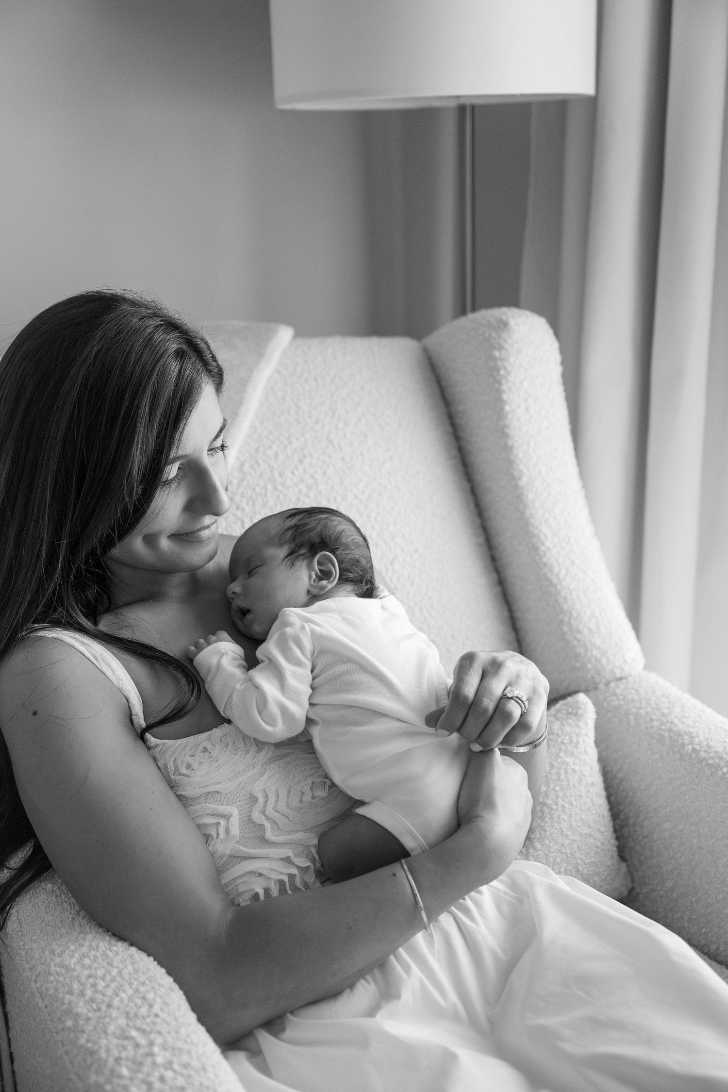 Black and white series of tender moments with newborn on white armchair.