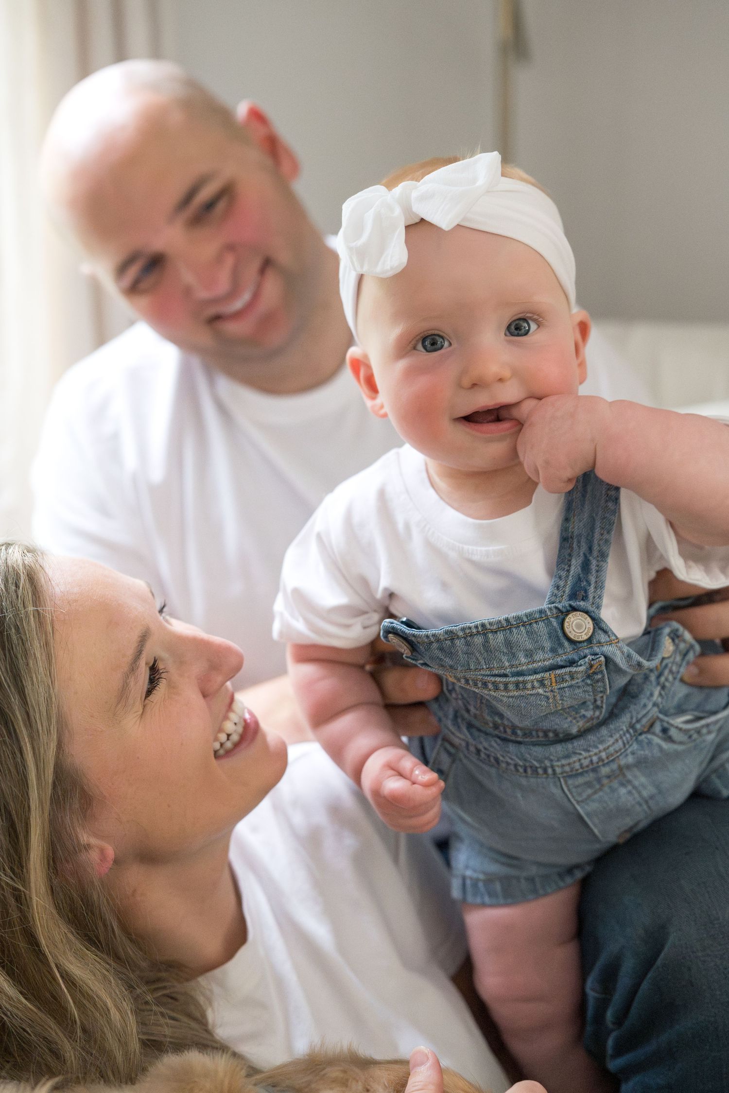 Playful interaction between parent and baby wearing denim overalls.