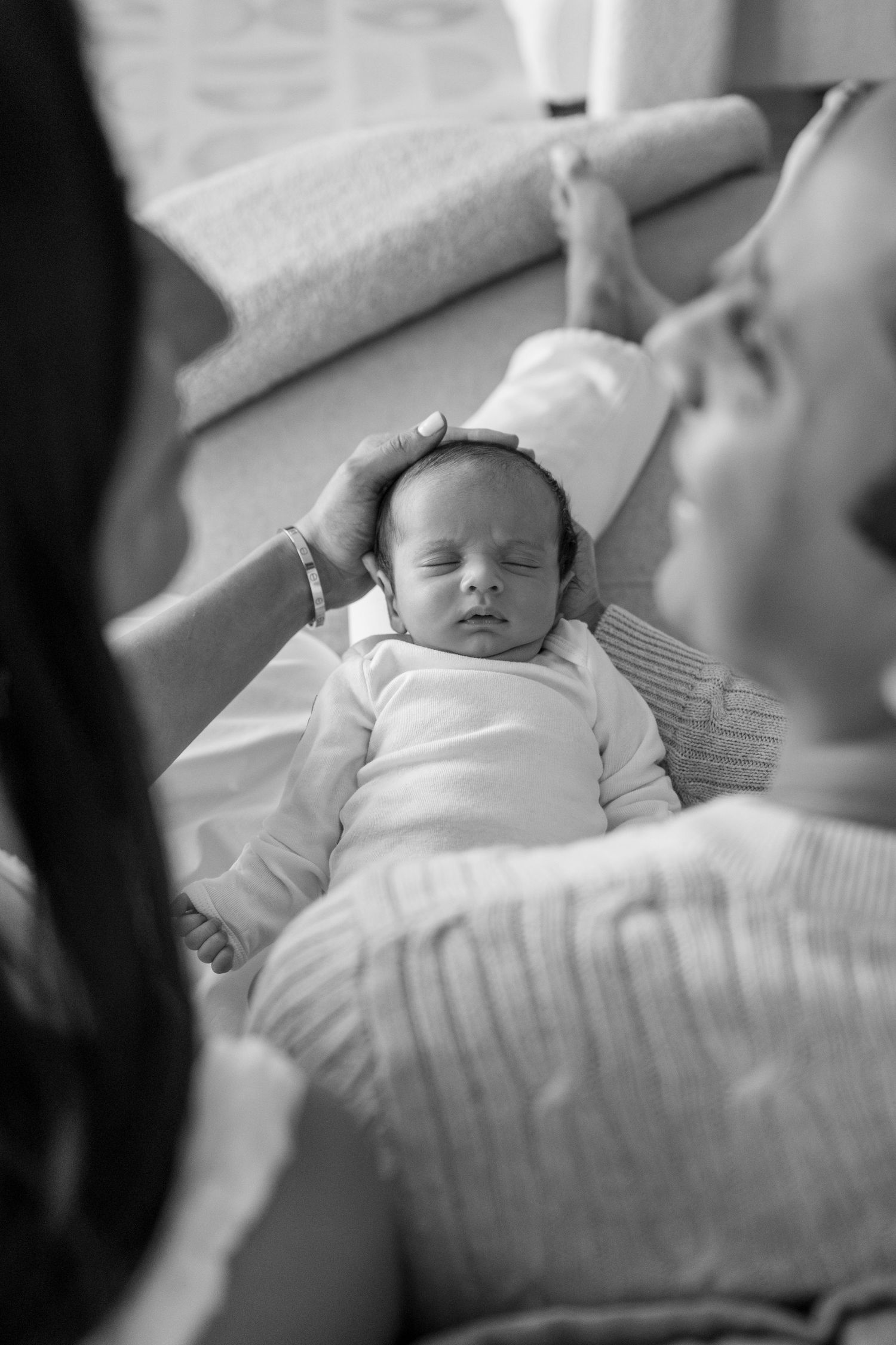 Overhead view of sleeping newborn baby in white outfit on cozy bedding.