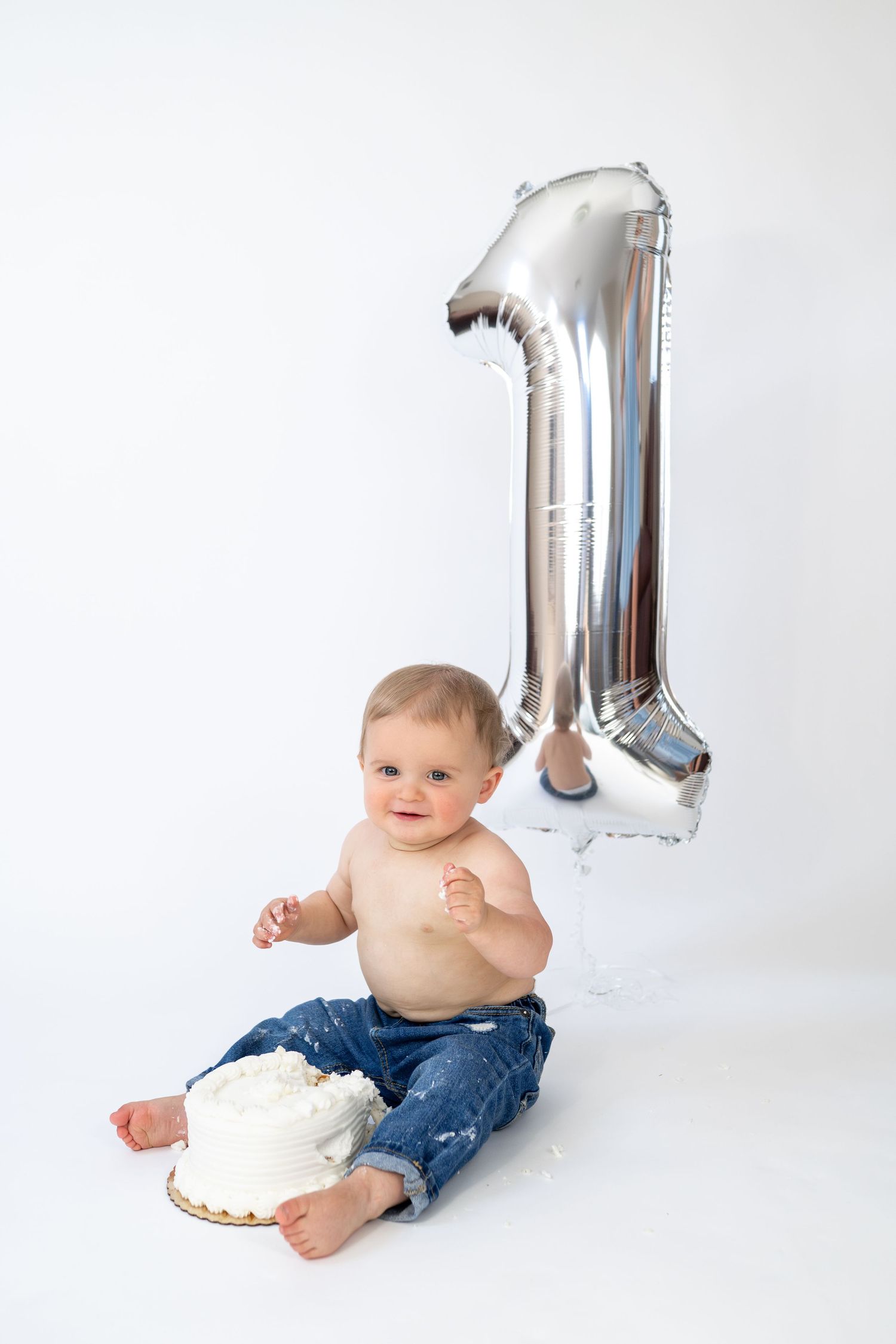 Baby's first birthday cake smash with silver number one balloon on white background.