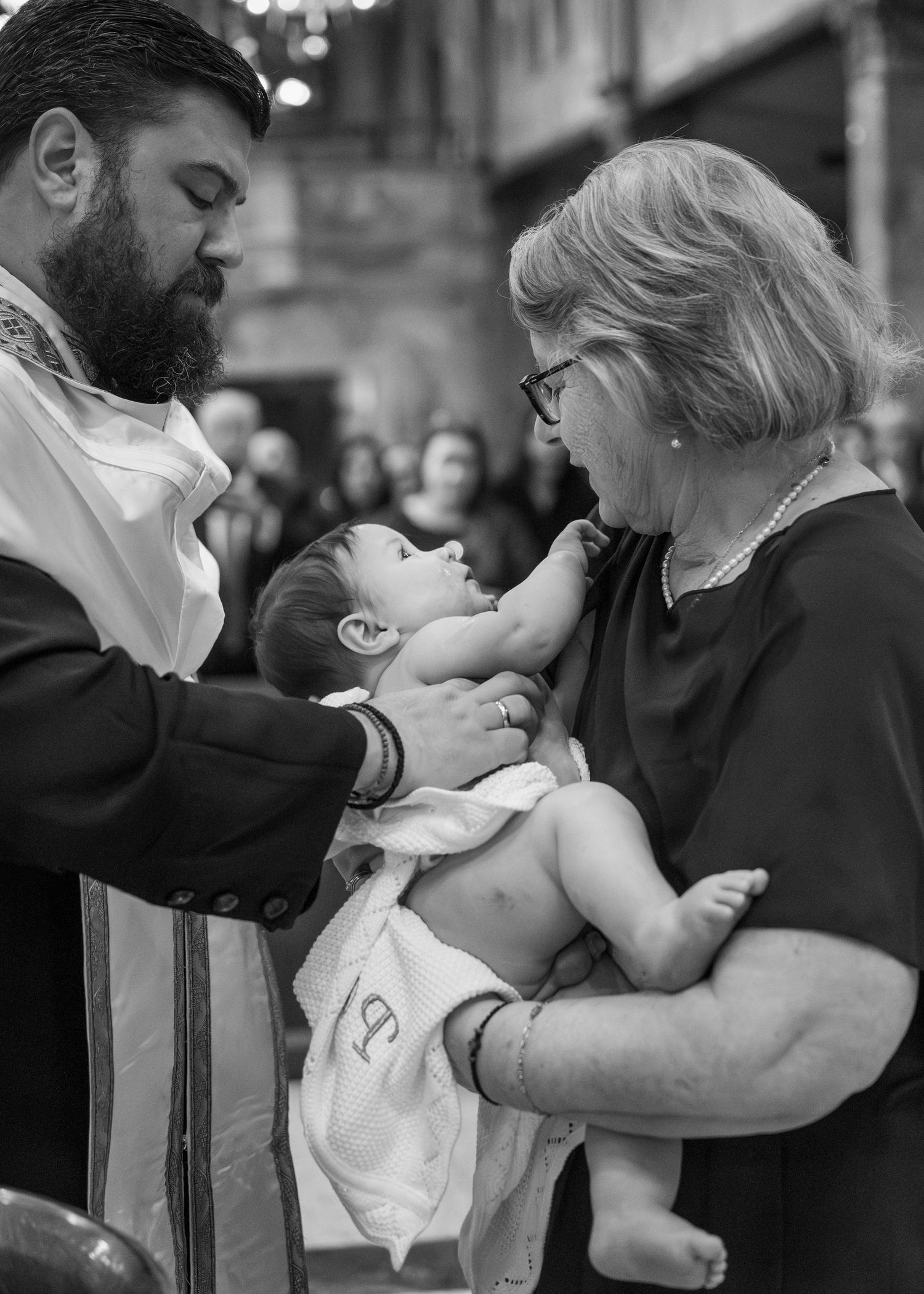 Black and white photo series showing tender moments between a baby and adults during a baptism ceremony.