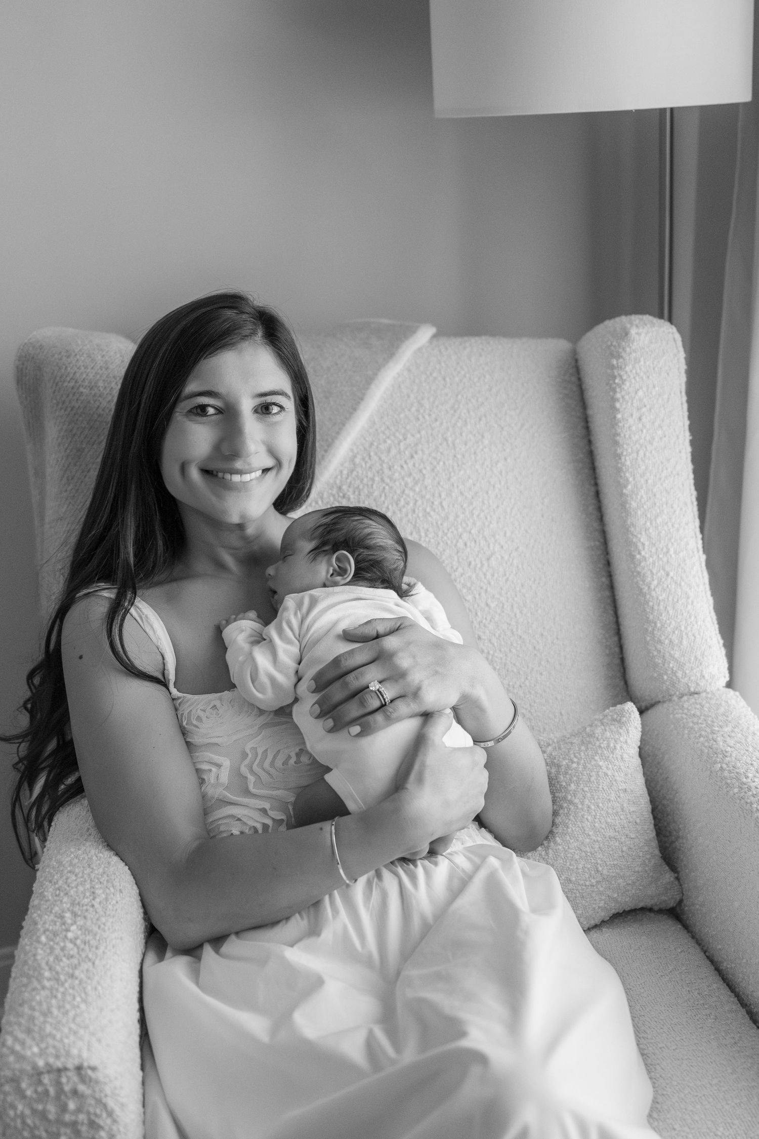 Sweet moment with sleeping newborn in cozy white armchair.