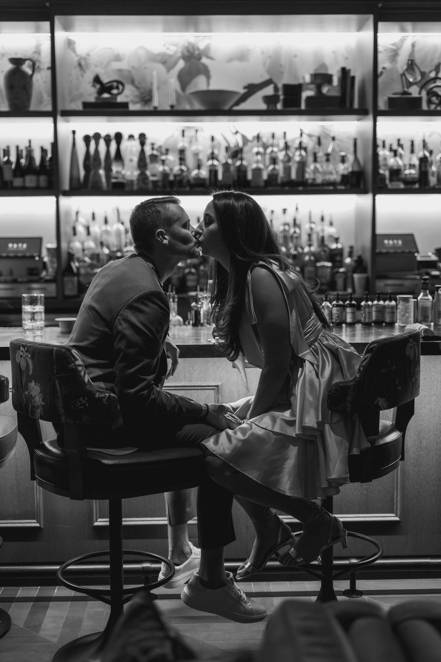 A black and white series of silhouettes showing people relaxing at a bar counter in progressive stages of reclining.