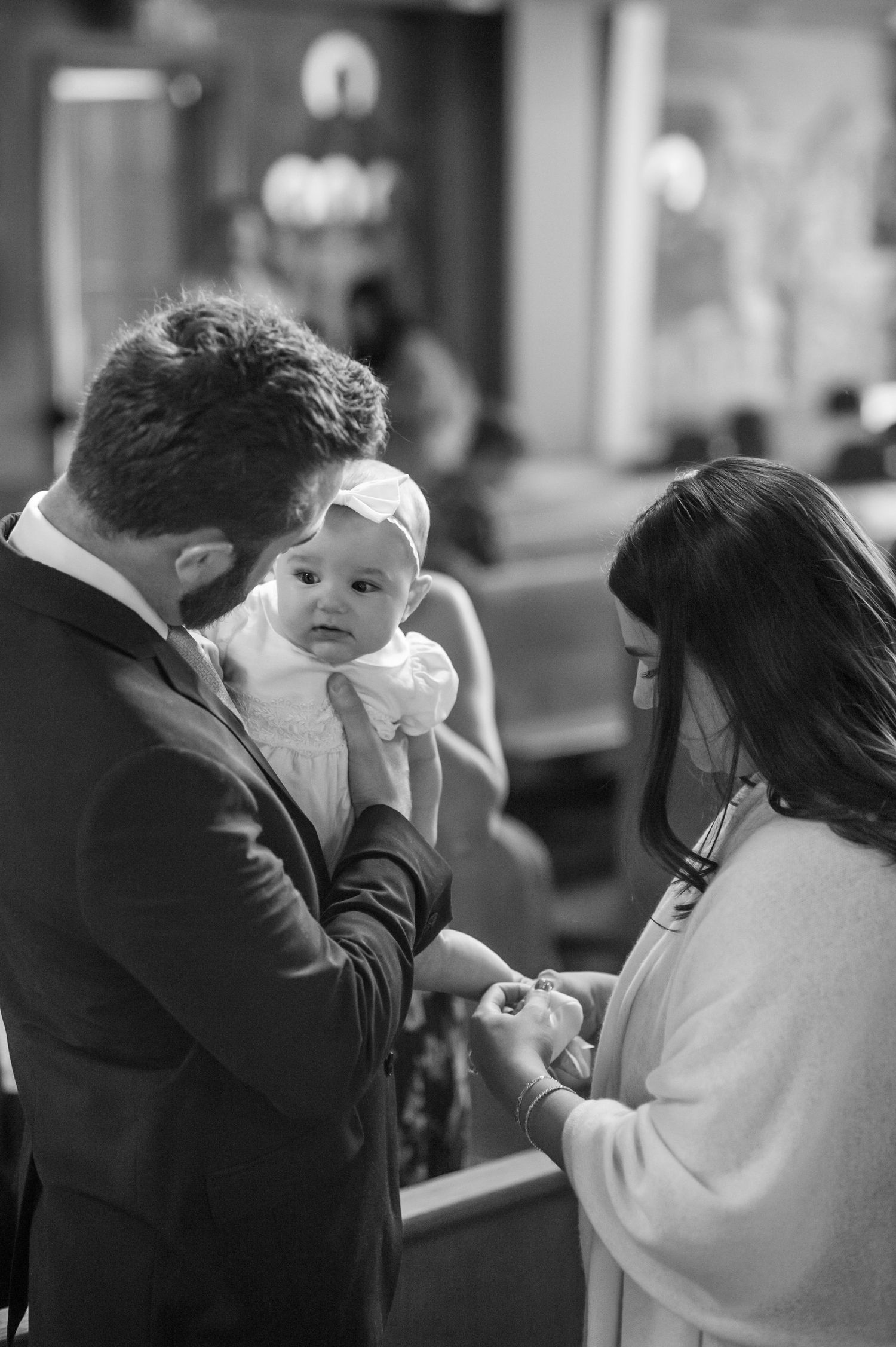 A tender baptism moment captured in black and white inside a church setting.
