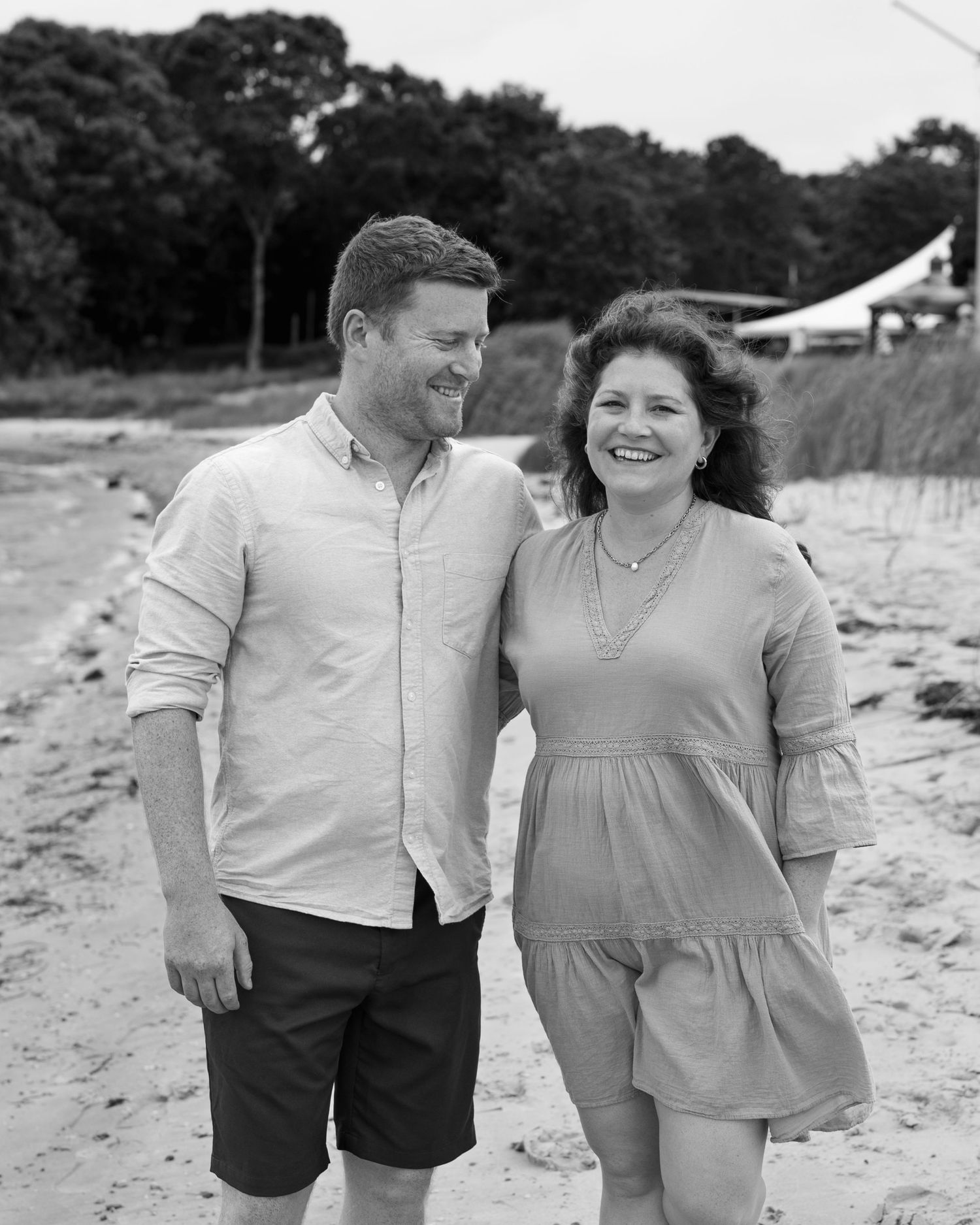 A couple walking together on the beach in black and white.
