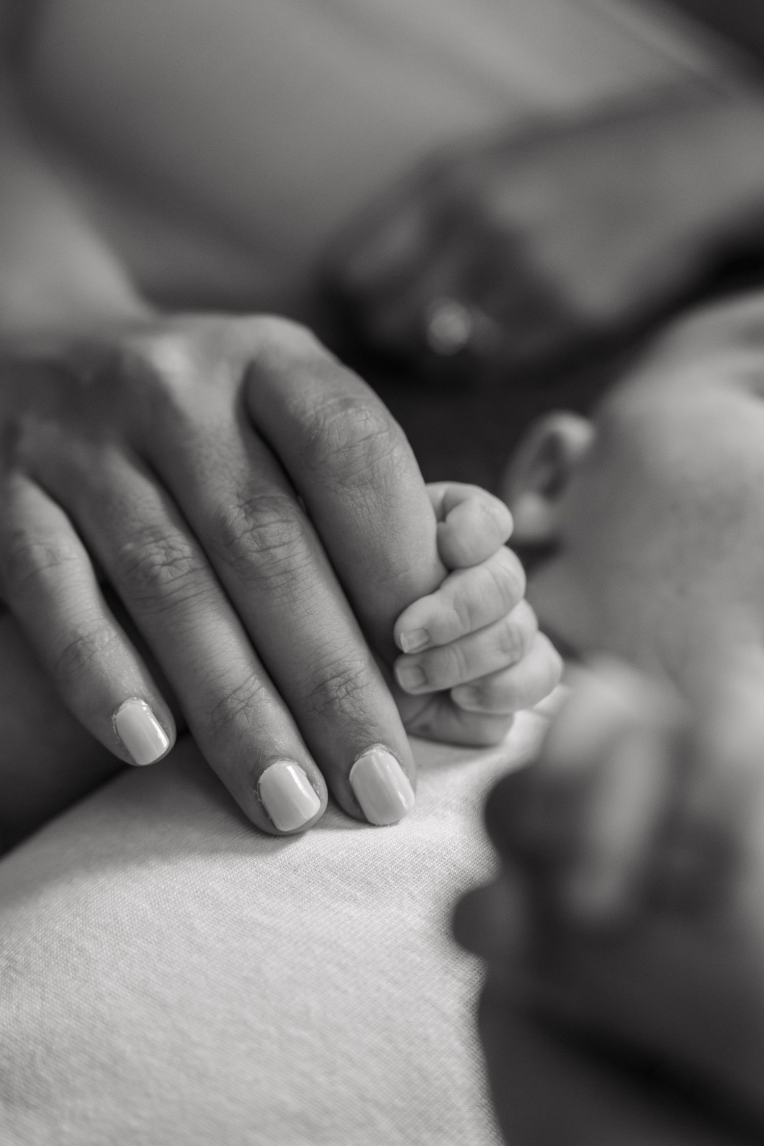Black and white macro shot of gentle hands resting on a soft surface.