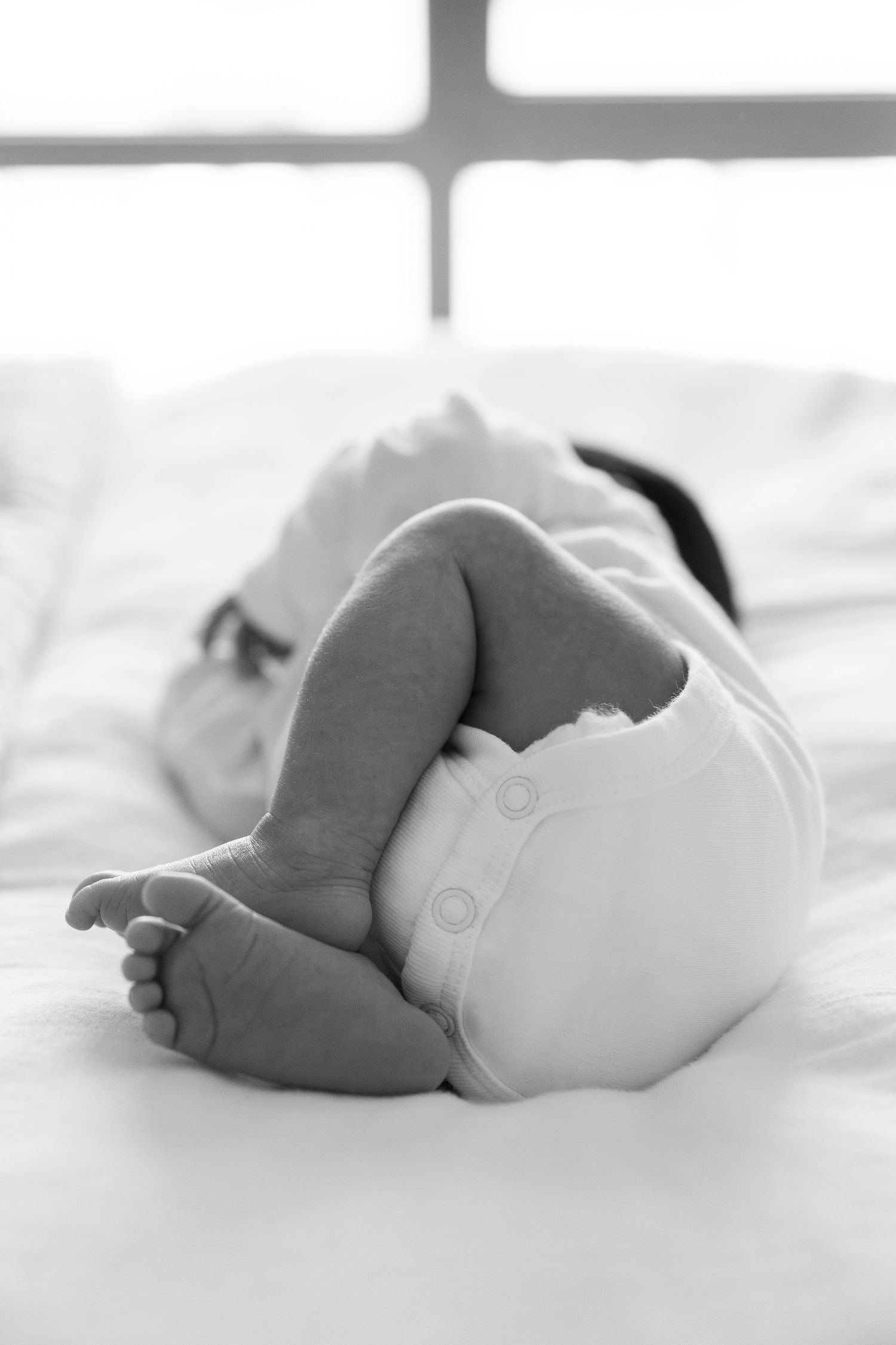 Artistic black and white photos of baby feet and details against white bedding.