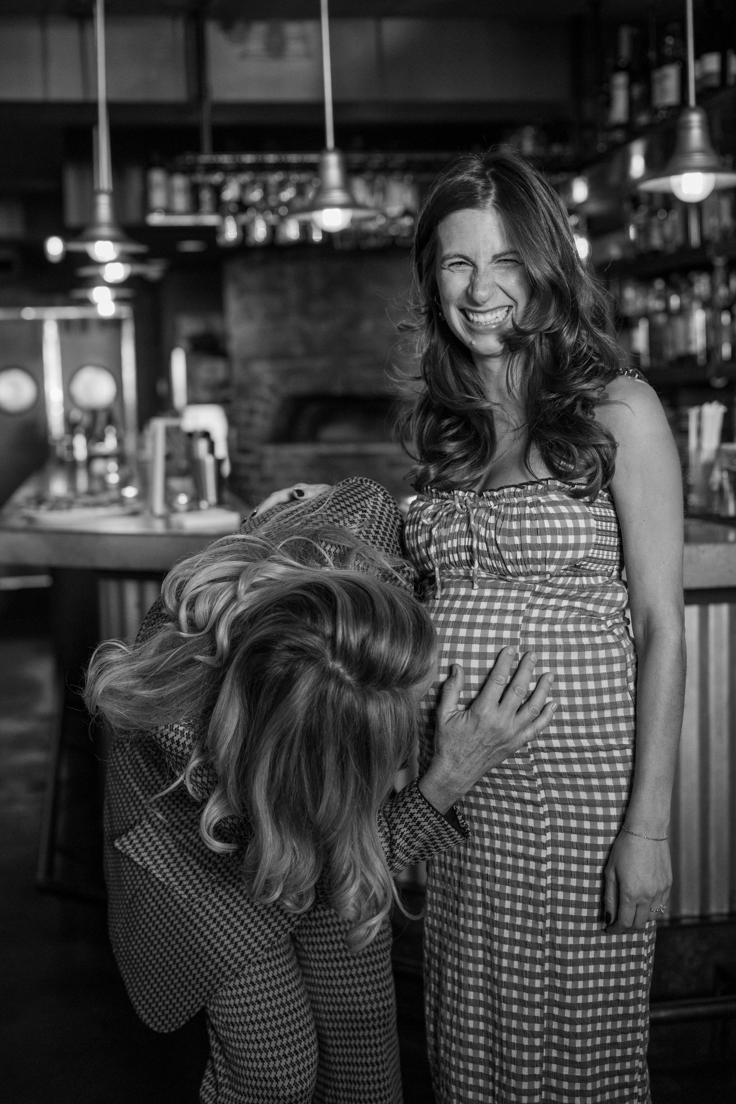 Friends sharing an intimate moment of laughter in black and white photography.