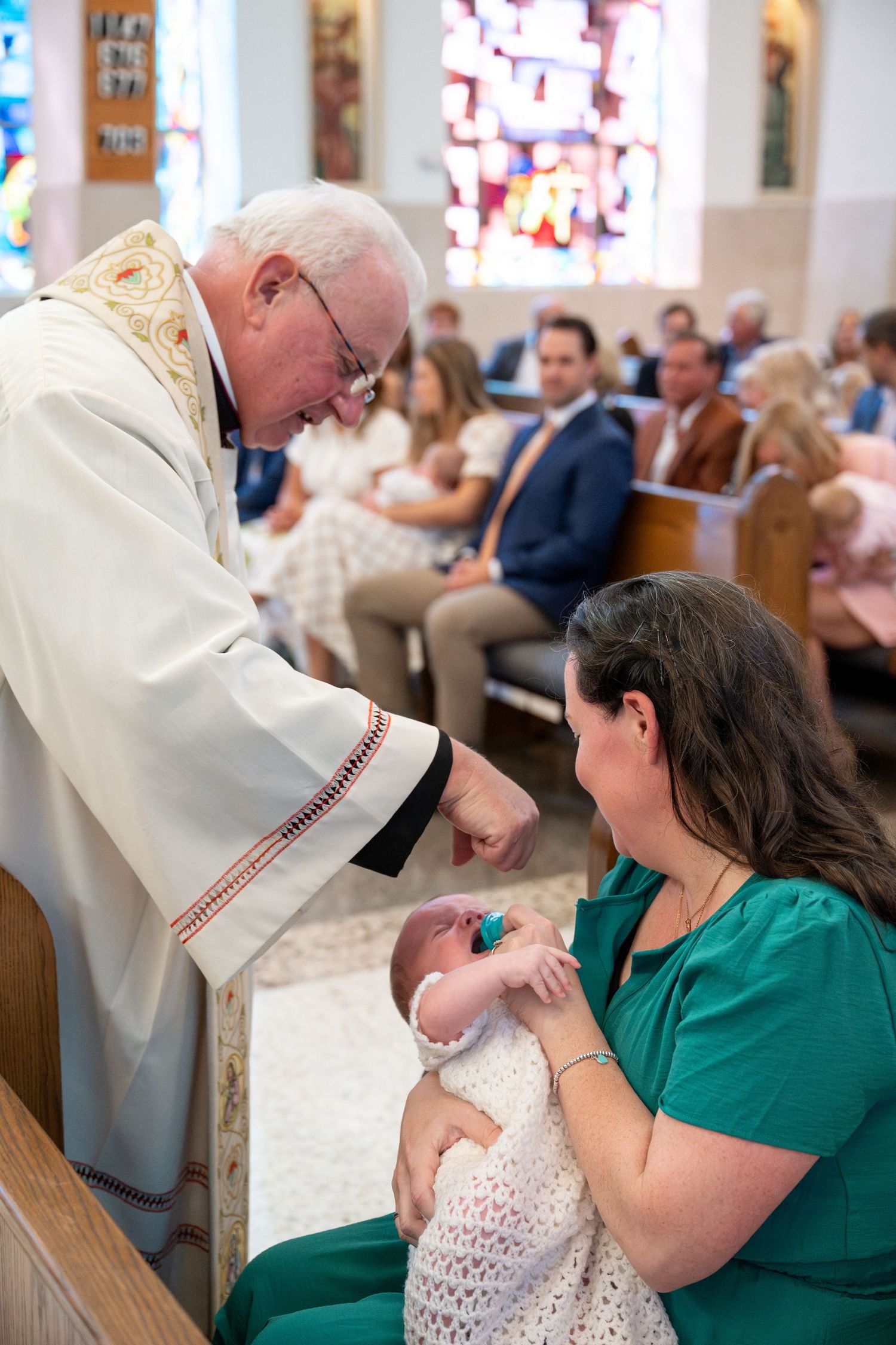 A priest performs a baptism ceremony for an infant in a traditional church setting.