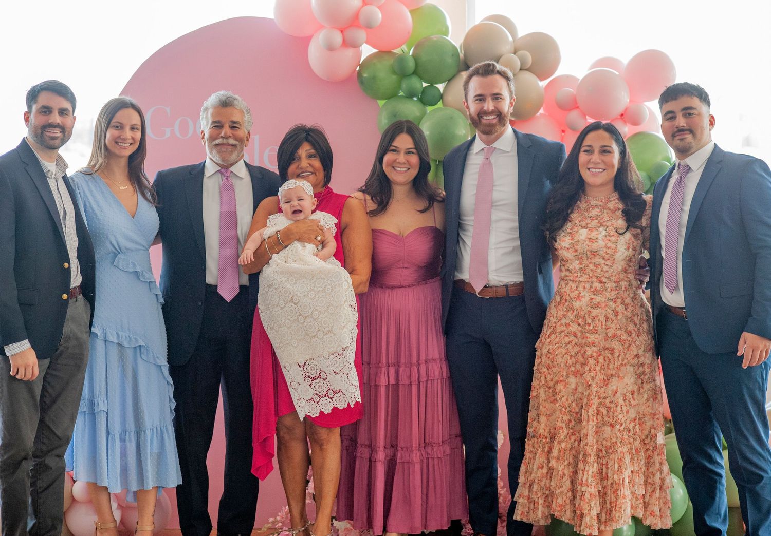 A group of people wearing formal attire and colorful dresses pose together at a special event.