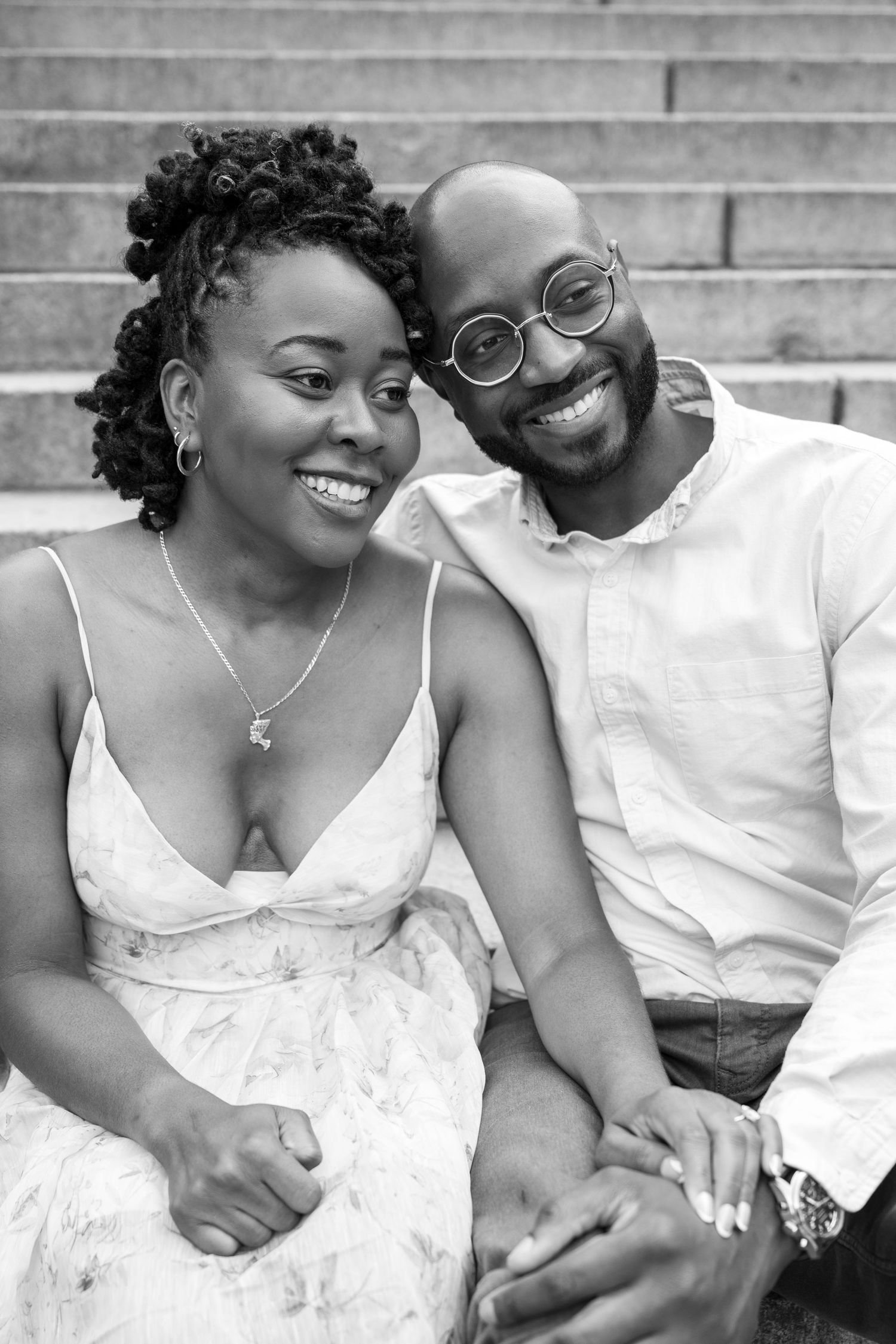 A couple in white attire shares intimate moments on concrete steps during a photo session.