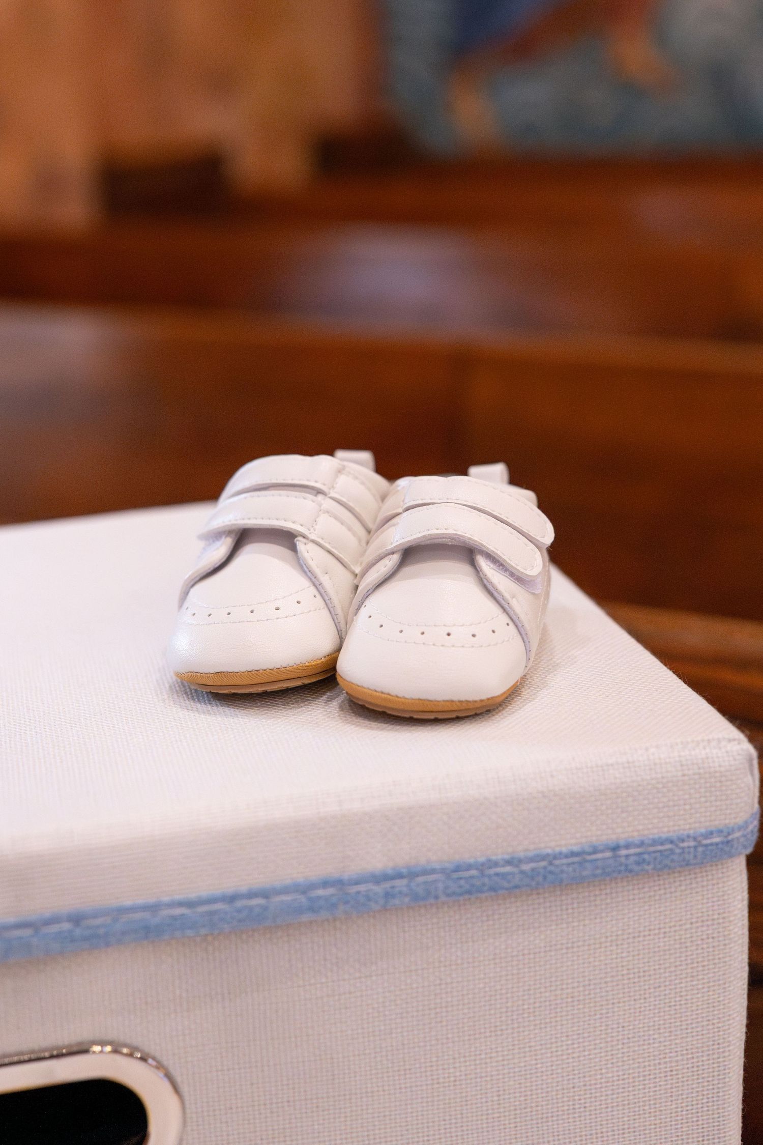 White baby shoes rest on a light-colored surface in a series of progressive close-up shots.