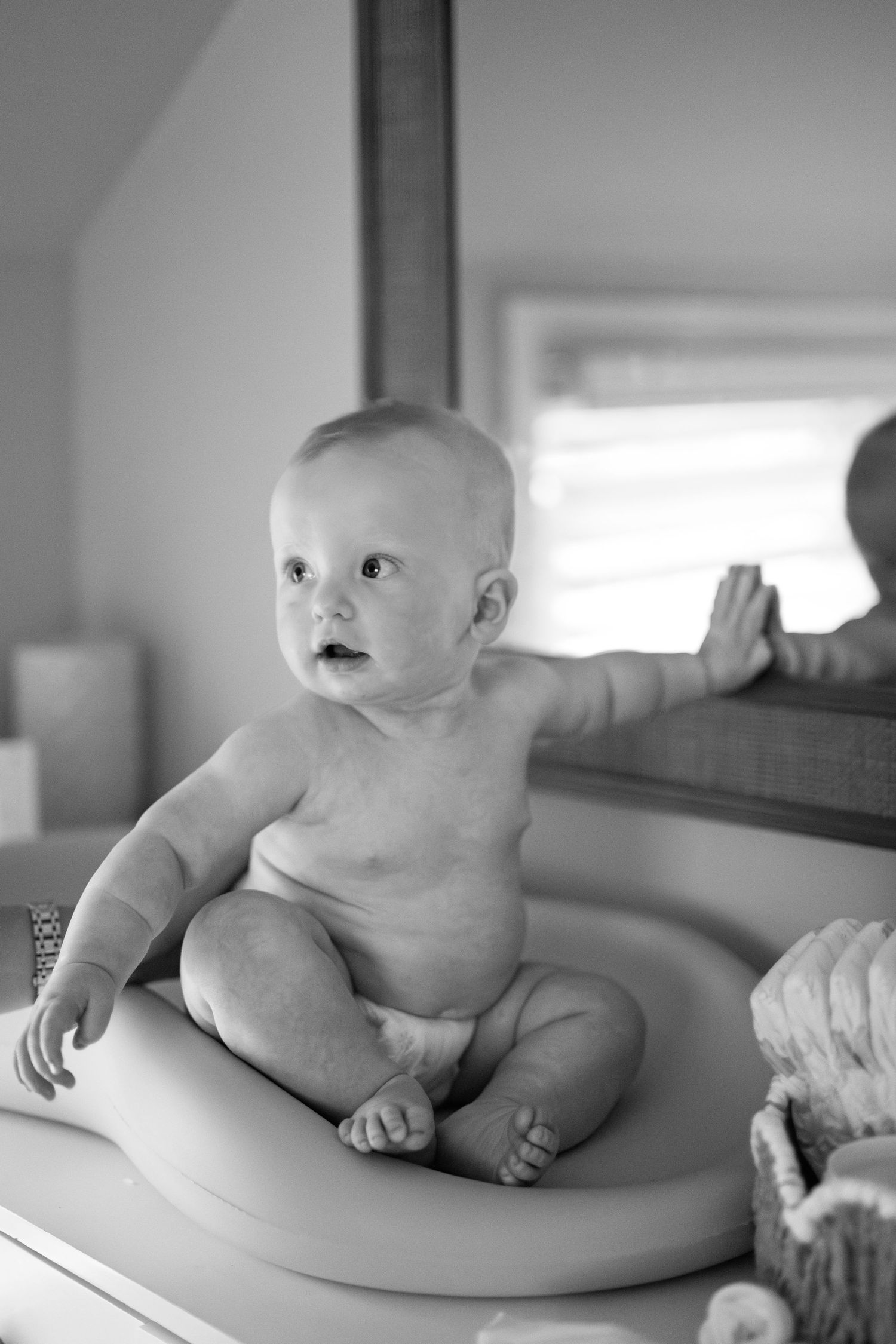 Black and white images of a baby resting on a changing table in various candid poses.