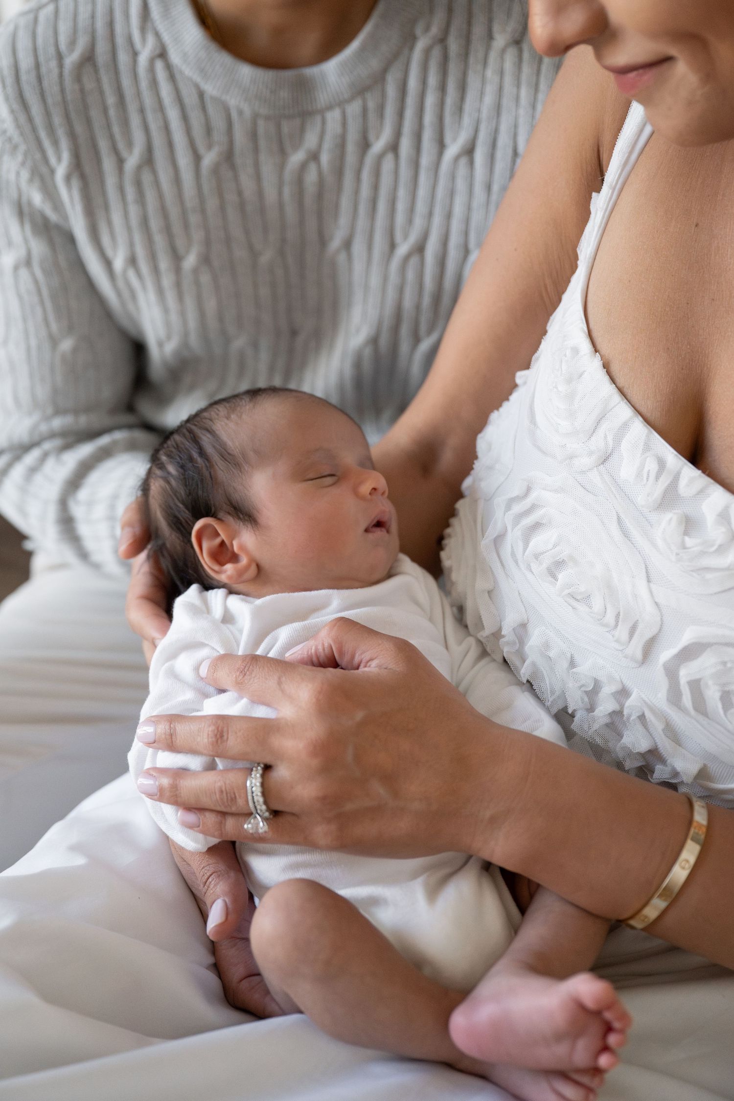 Close-up shots of parents cradling newborn baby in white clothing.